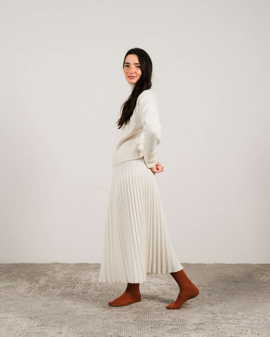Ivory roll-up cuff cashmere turtleneck sweater paired with matching skirt. Soft knitwear from HenryPawHaven's Italian-crafted collection.