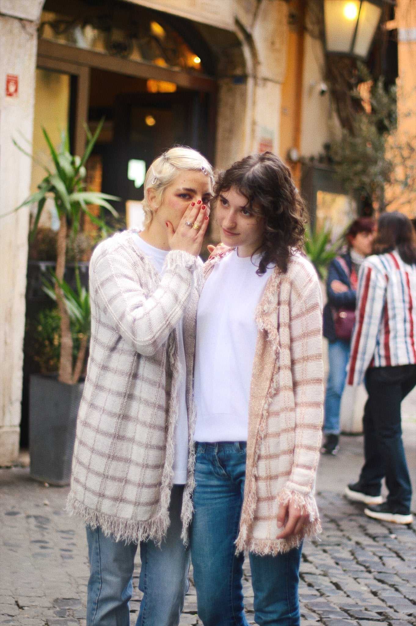 Tenné Olivia Midi Cardigans in pastel tones with Lurex Inserts, worn by two women in urban setting, highlighting fringe details and soft knit texture.