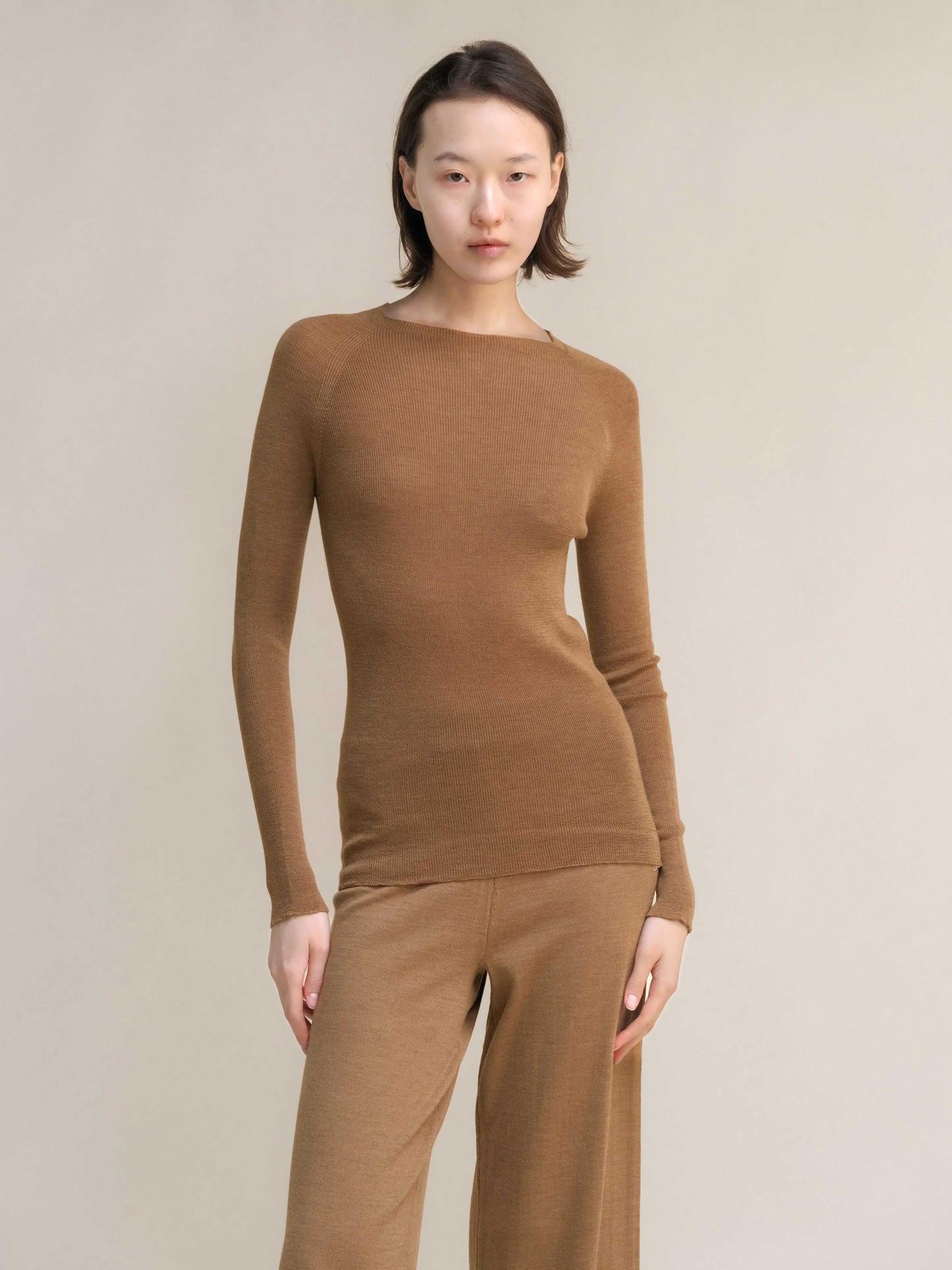 Camel brown slim fit ribbed crewneck in extra fine merino wool, paired with matching pants. Breathable, seamless knitwear for cozy sophistication.