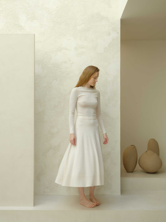 Ivory slim fit ribbed crewneck in extra fine merino wool, paired with matching skirt. Lightweight, seamless knitwear for elegant comfort.