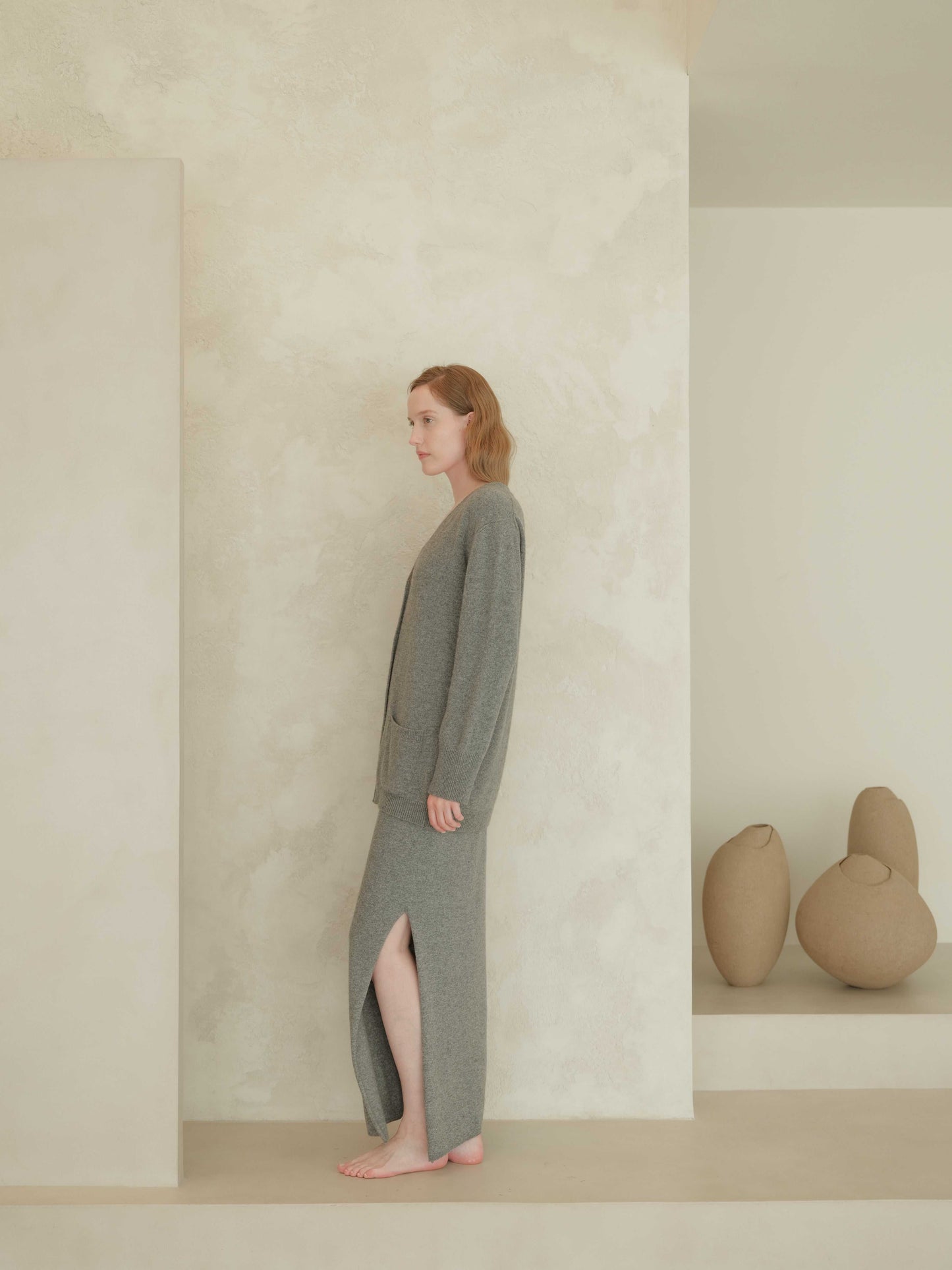 Grey cashmere skirt with side slit and seamless cardigan. Sustainable Italian knitwear crafted for comfort and refined style.