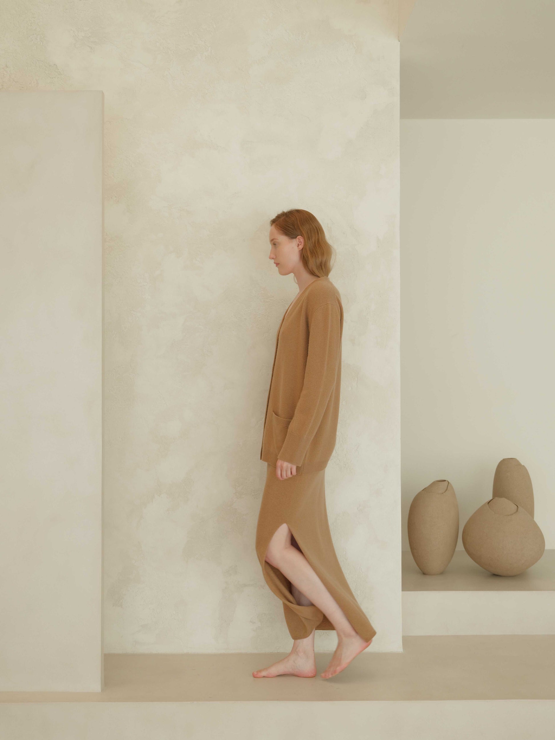 Camel cashmere skirt with side slit and matching cardigan. Seamless Italian knitwear offering elegance and ethical craftsmanship.