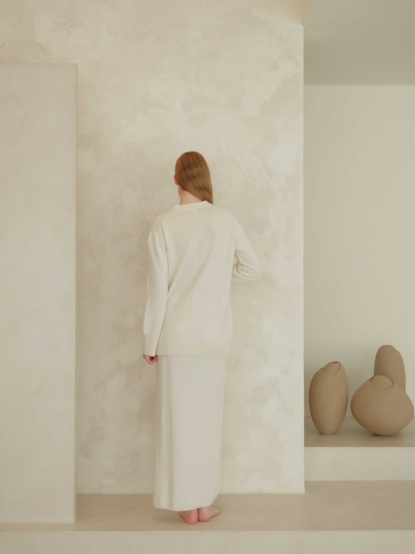 Ivory cashmere skirt with side slit, styled with matching knitwear. Luxurious Italian knitwear crafted for minimalist sophistication.