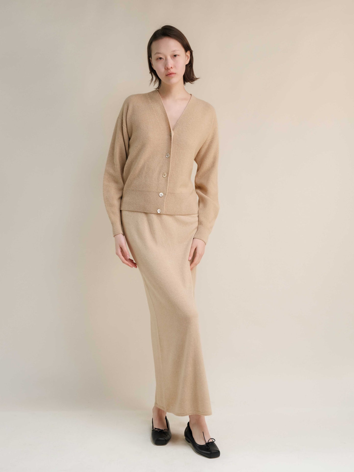 Beige cashmere skirt with side slit and matching cardigan. Premium Italian knitwear designed for timeless, sustainable fashion.