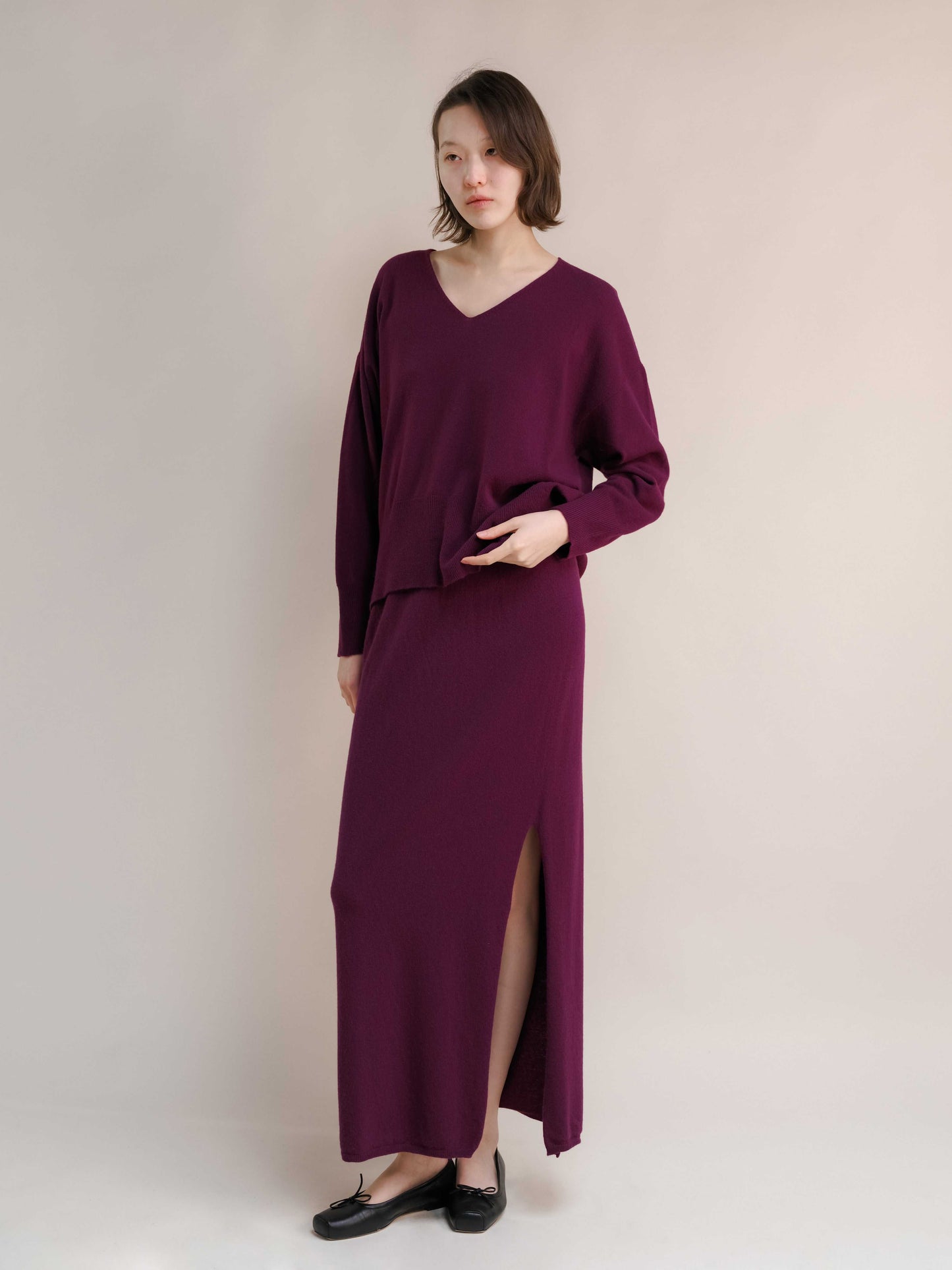 Plum cashmere skirt with side slit and V-neck knit top. Seamless Italian knitwear designed for comfort and modern sophistication.