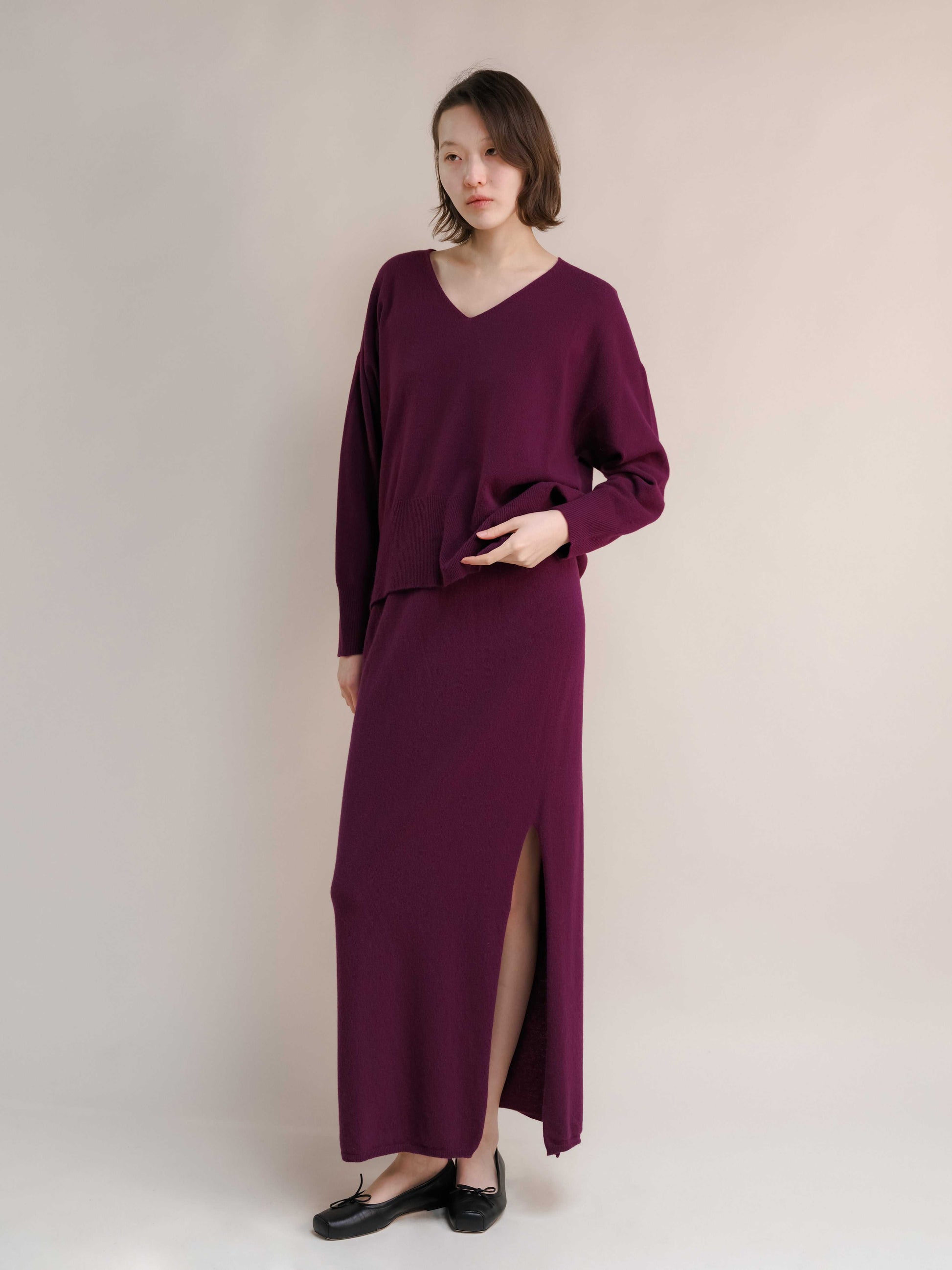 Plum cashmere skirt with side slit and V-neck knit top. Seamless Italian knitwear designed for comfort and modern sophistication.
