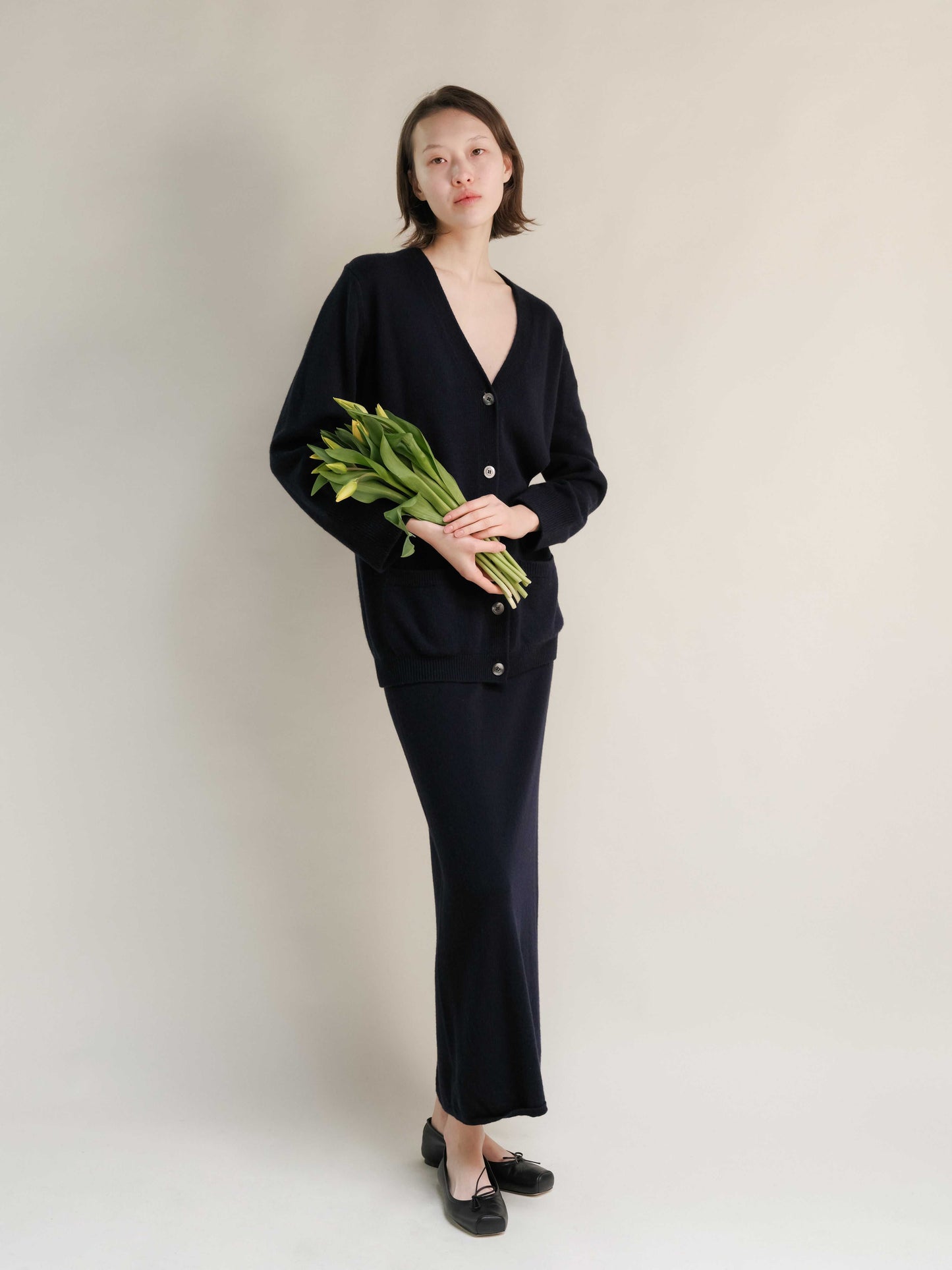 Navy cashmere skirt with side slit, styled with matching cardigan. Elegant Italian knitwear made for sustainable fashion lovers.