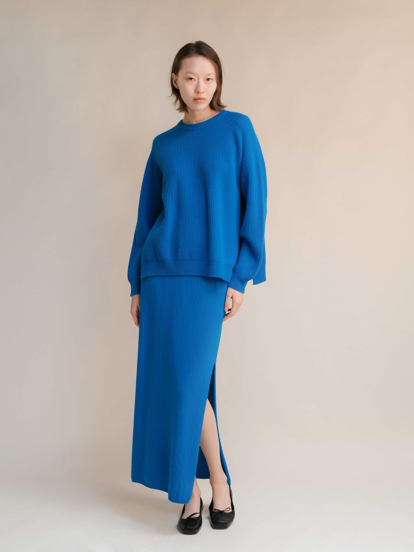 Cashmere skirt with side slit in cobalt blue, styled with matching knit top. Seamless Italian knitwear for premium comfort and elegance.