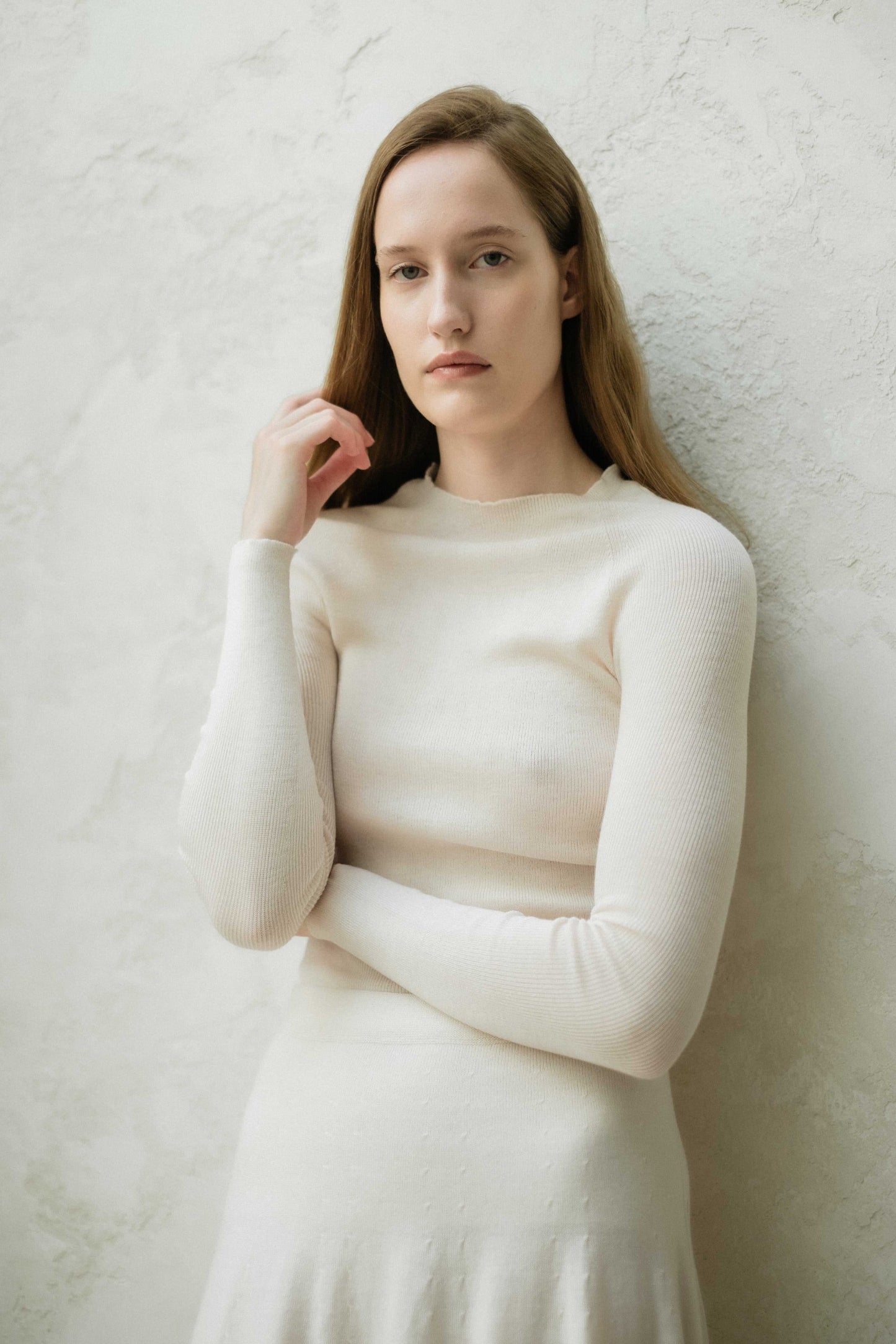 Close-up of ivory slim fit ribbed crewneck in extra fine merino wool. Seamless, breathable knitwear with a soft, elegant texture.