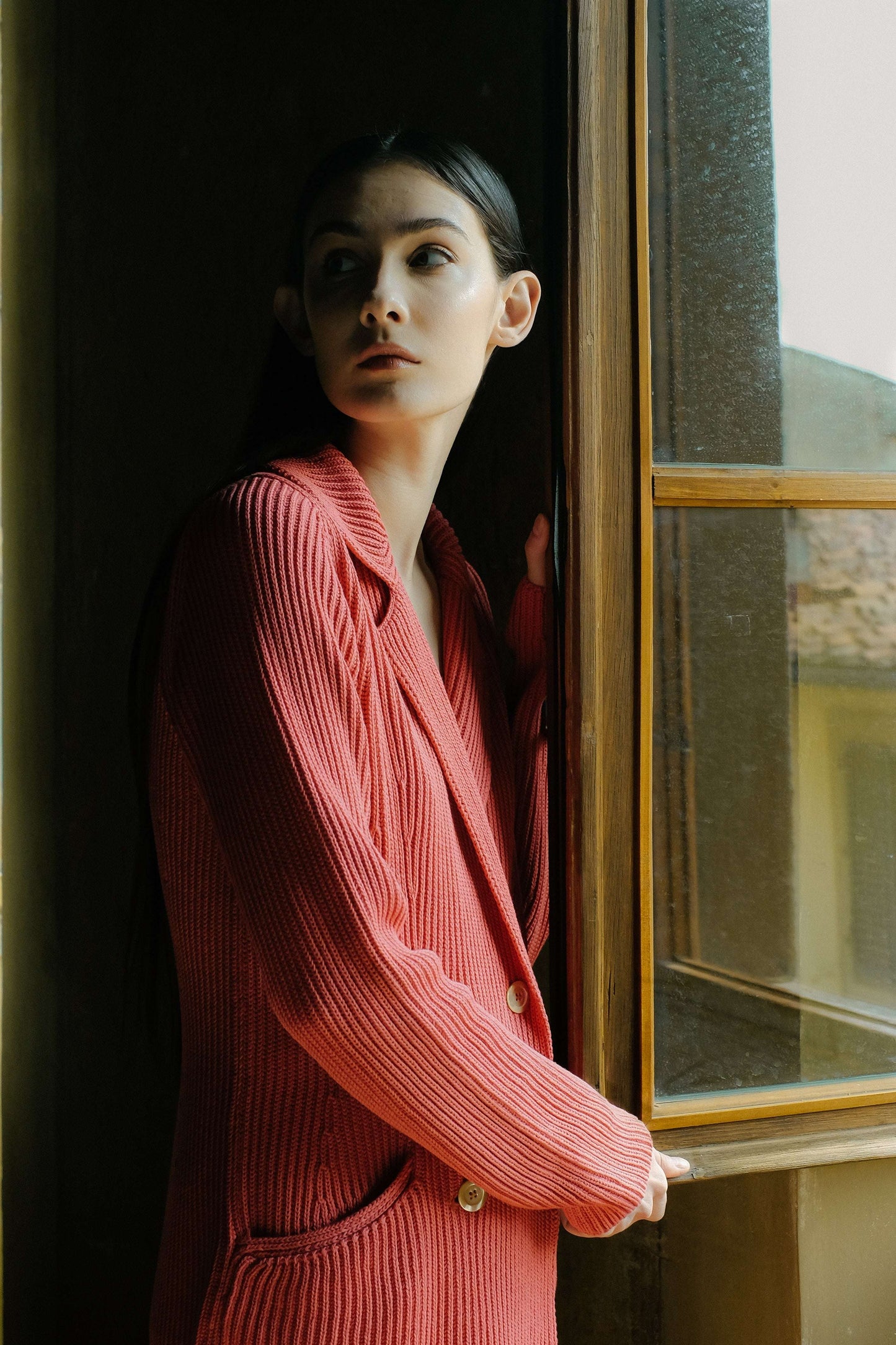 Red Fine Cotton Double Breasted Knit Jacket with fisherman's rib knit and pearl buttons, worn by model near window. Elegant Italian outerwear by HenryPawHaven.