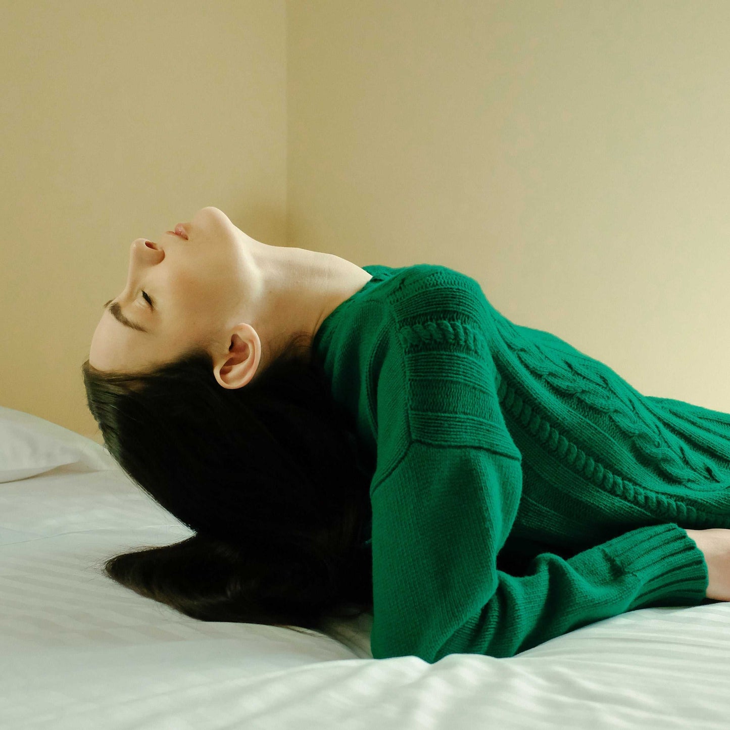 Green Cashmere Mix Cable Knit Sweater worn while reclining on a bed. Soft, sustainable knitwear from HenryPawHaven for relaxed elegance.