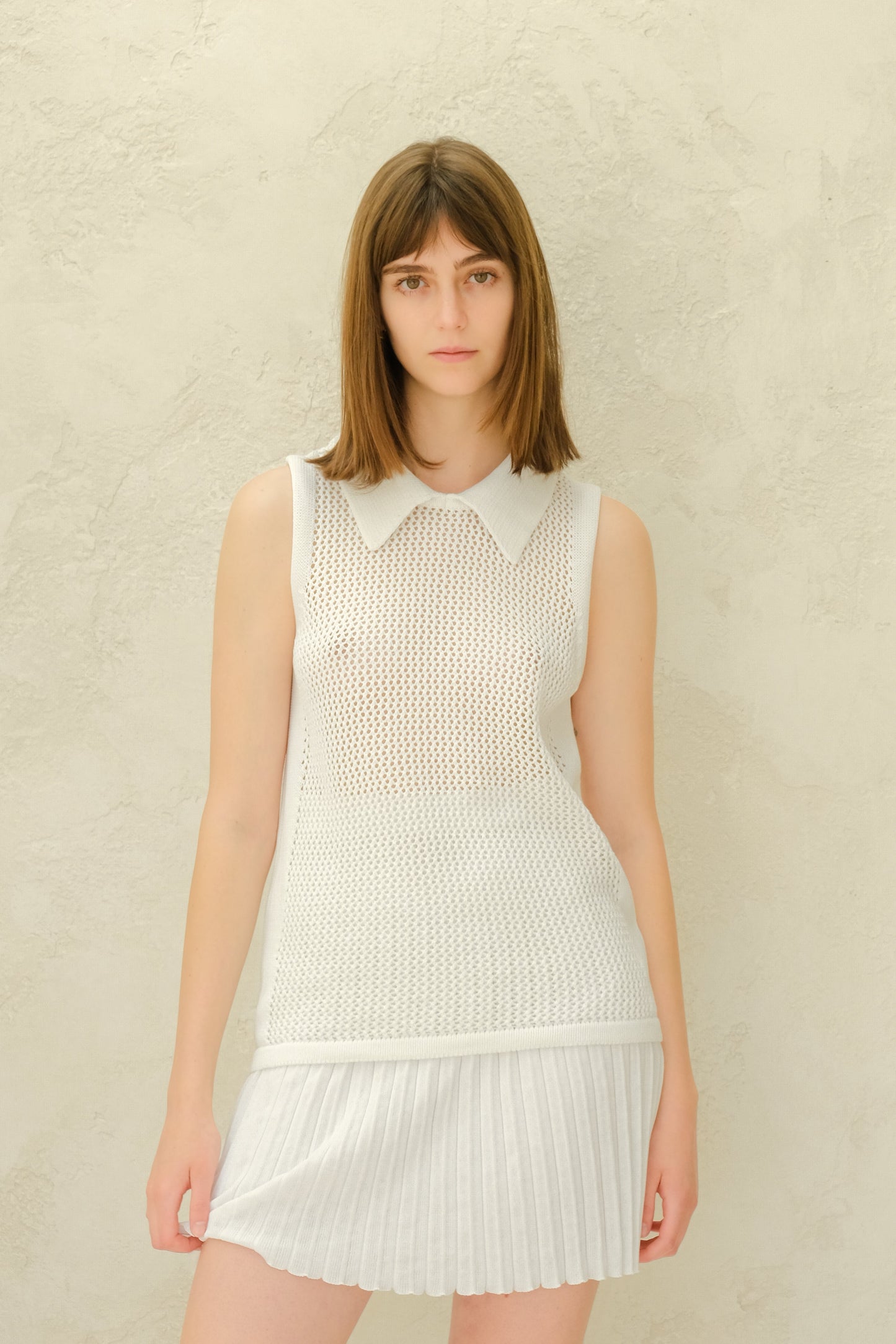 White Fine Crochet Polo Tank Top styled with pleated skirt. Lightweight and breathable Italian knitwear in merino wool.