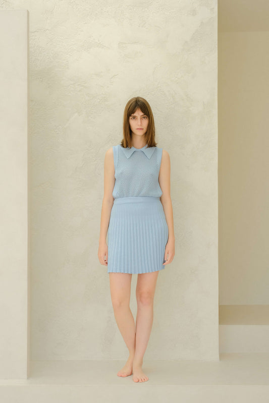Model in light blue plissé mini skirt and knit top