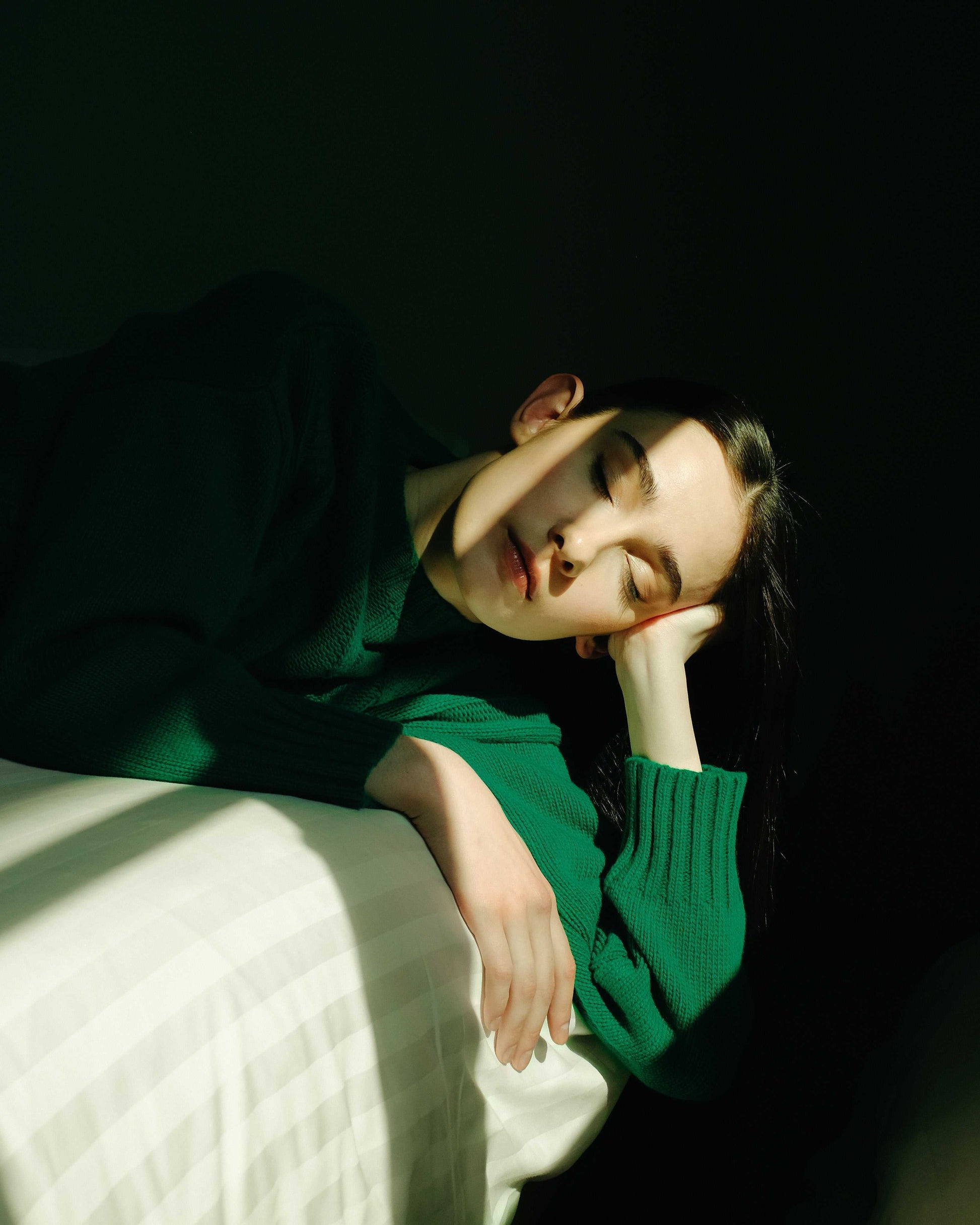 Green Cashmere Mix Cable Knit Sweater worn while resting on a bed. Cozy sustainable knitwear from HenryPawHaven for relaxed elegance.