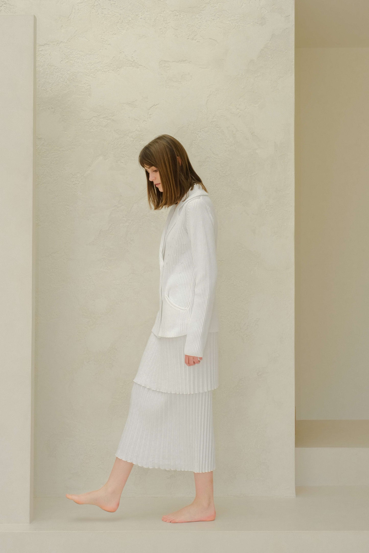 Side view of white double breasted knit jacket in fisherman's rib, crafted from 100% combed cotton. Minimalist elegance by Lèmme.