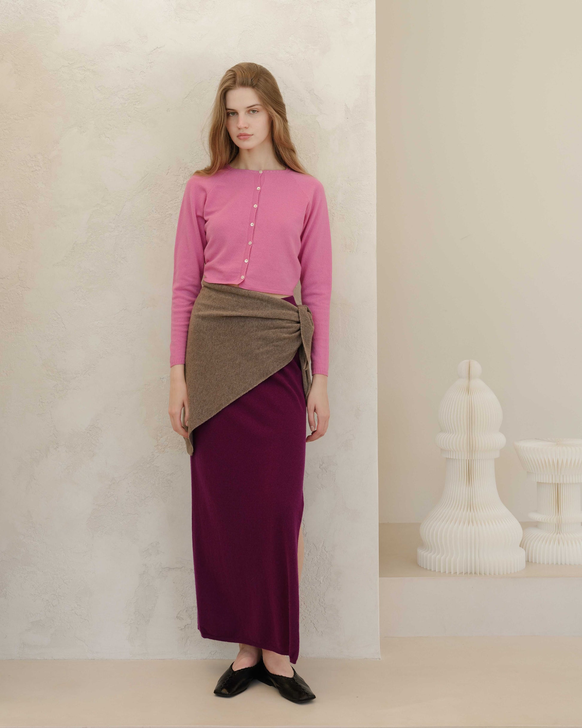 Plum cashmere skirt with taupe wrap and side slit, styled with pink knit top. Sustainable Italian knitwear for refined everyday wear.
