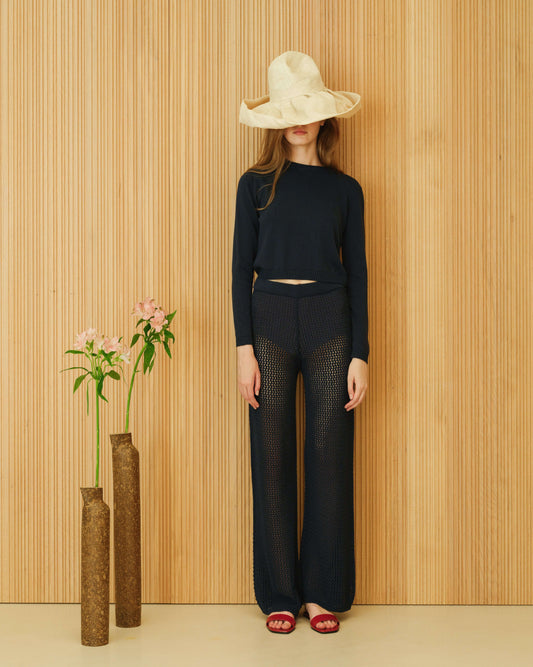 Black Crochet Cotton Pants from HenryPawHaven, Italian-crafted openwork trousers paired with long-sleeve top and wide-brim hat.