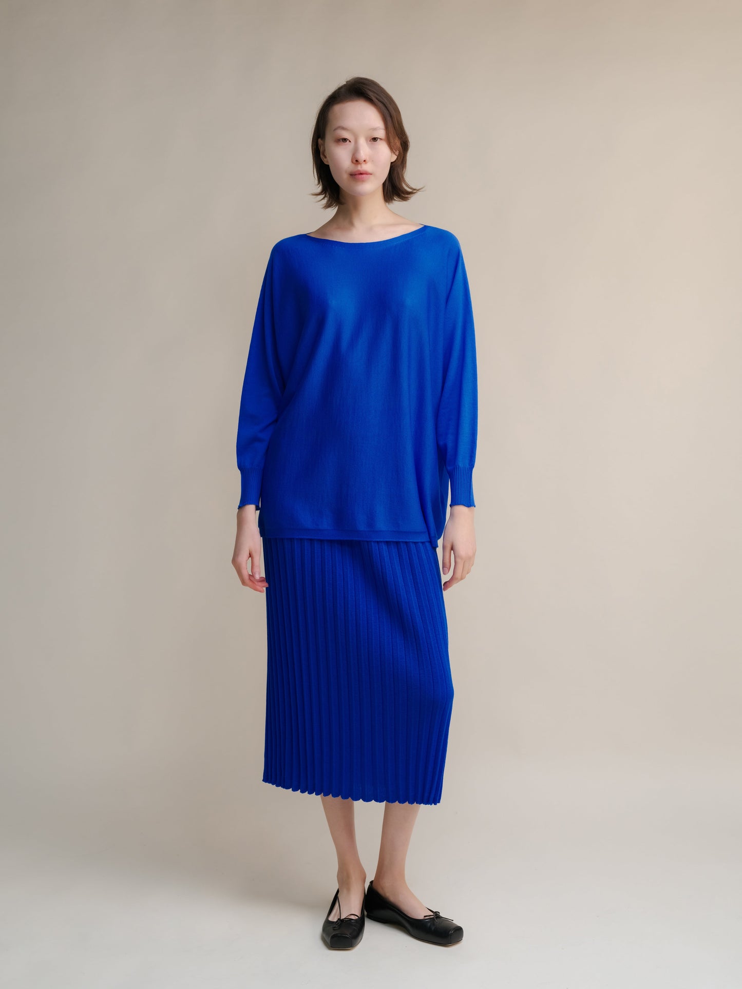 Royal blue Extra Fine Merino Wool Boat Neck Oversized Sweater paired with matching pleated skirt, Italian seamless knitwear.