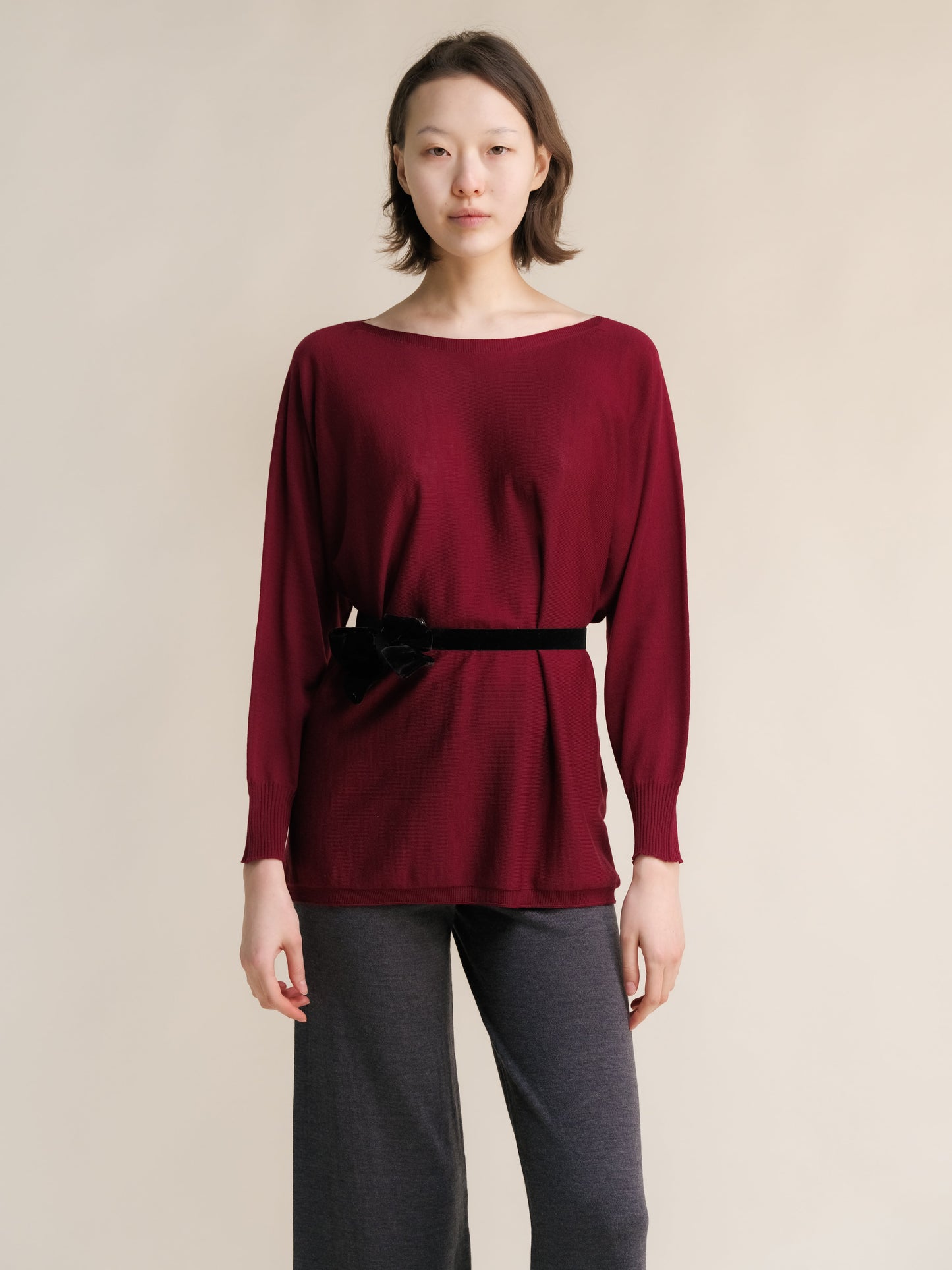 Burgundy Extra Fine Merino Wool Boat Neck Oversized Sweater styled with black belt, Italian knitwear with elegant ribbed cuffs.