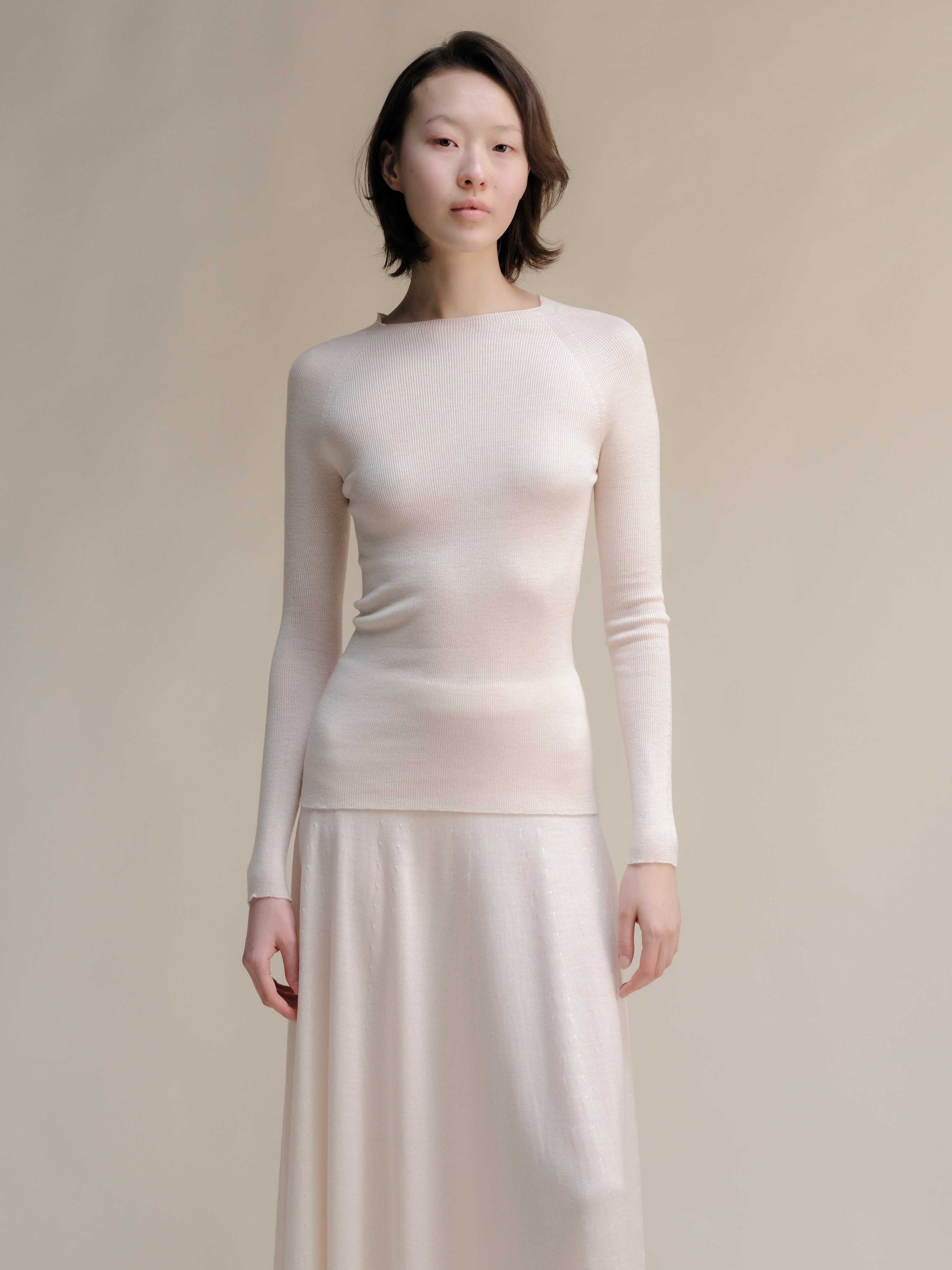 Light beige slim fit ribbed crewneck in extra fine merino wool, paired with matching skirt. Seamless, breathable knitwear with a soft sheen.