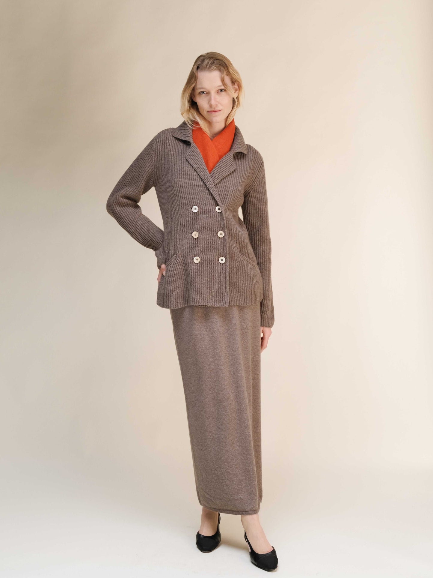 Taupe cashmere wool blend double breasted jacket styled with matching skirt, featuring elegant tailoring and functional pockets.