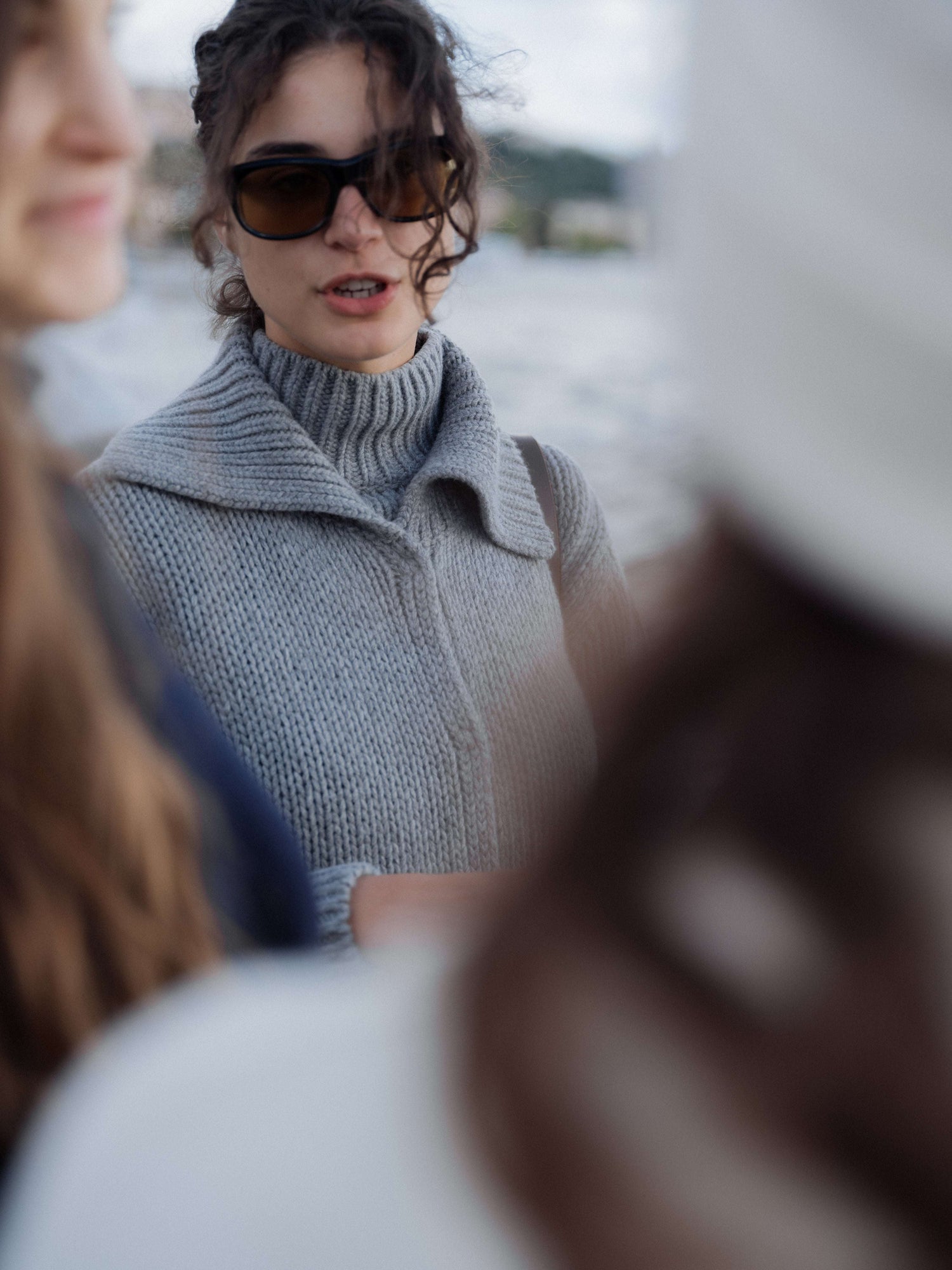 Chunky cashmere cardigan with wide collar and ribbed texture, worn by woman outdoors near water. Italian knitwear by HenryPawHaven.