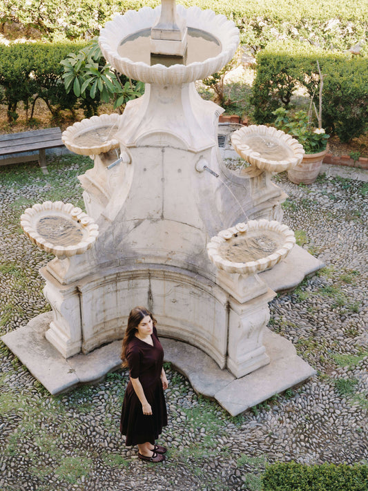 Model wearing Extrafine Merino Wool Short Sleeve Polo near fountain
