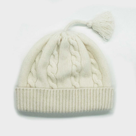 Portolano Baby Cashmere Hat in white with cable knit design and tassel. Soft 100% cashmere hat for infants, ideal for warmth and comfort.