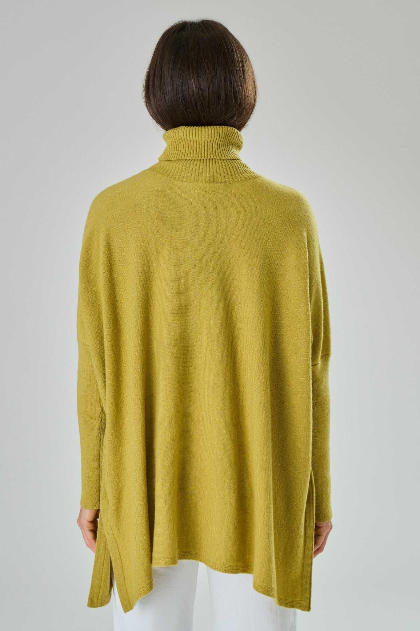Back view of Amalia Cashmere Blend Turtleneck Sweater in Blue by Tenné, showing loose drape and side slit details for added comfort.