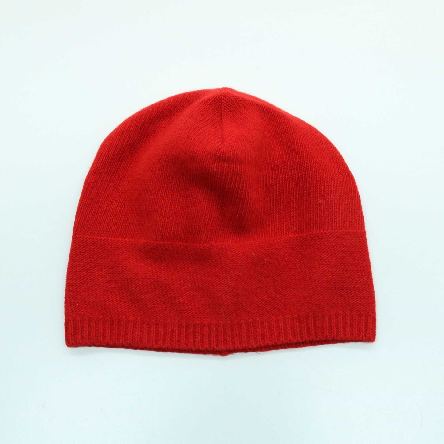 Red Portolano Women's Cashmere Slouchy Hat laid flat. Vibrant and warm 100% cashmere beanie with ribbed edge for a snug fit.