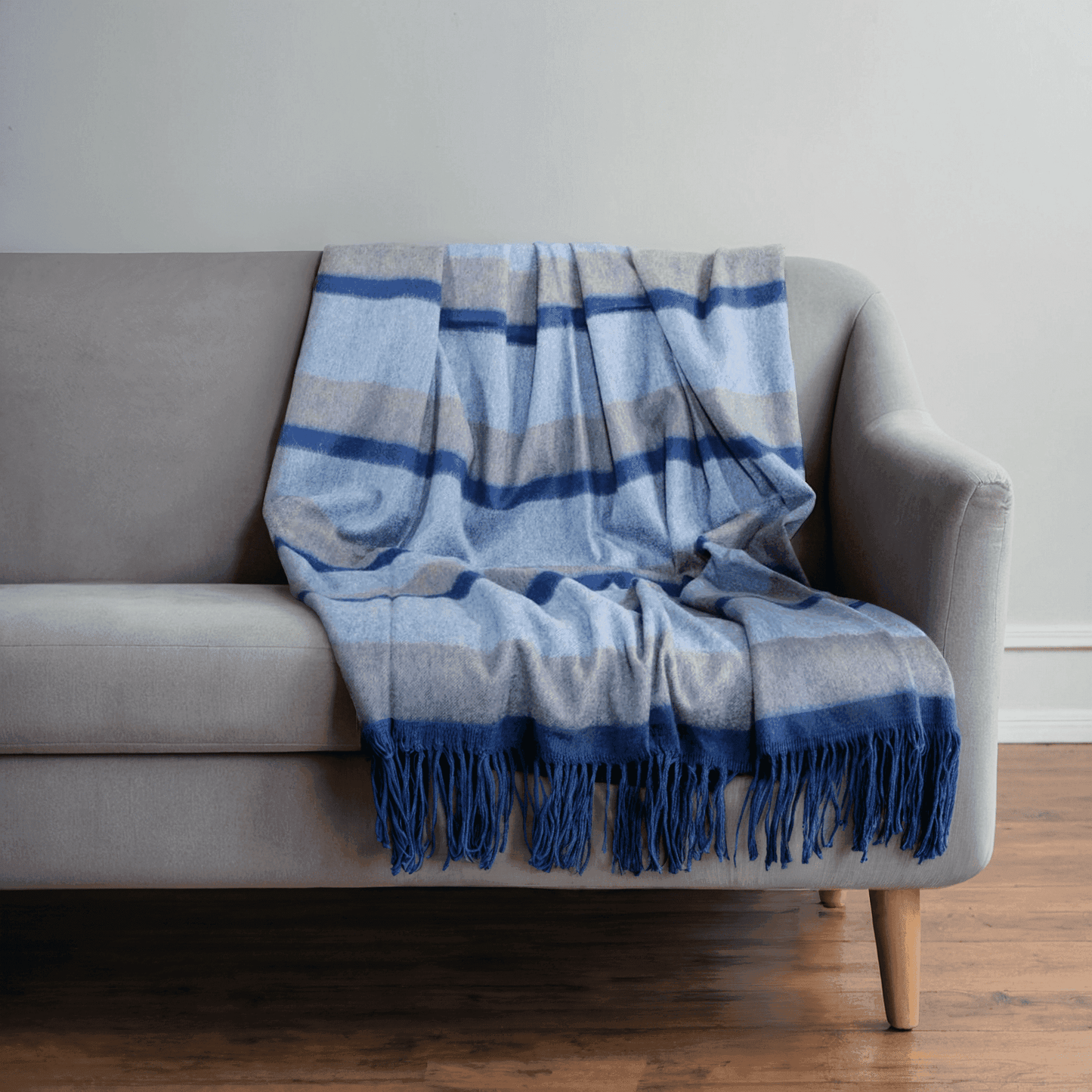 Cashmere Woven Throw - Cashmere Woven Throw | Premium Quality in blue and grey stripes with fringes, styled on a grey sofa for a cozy home accent.