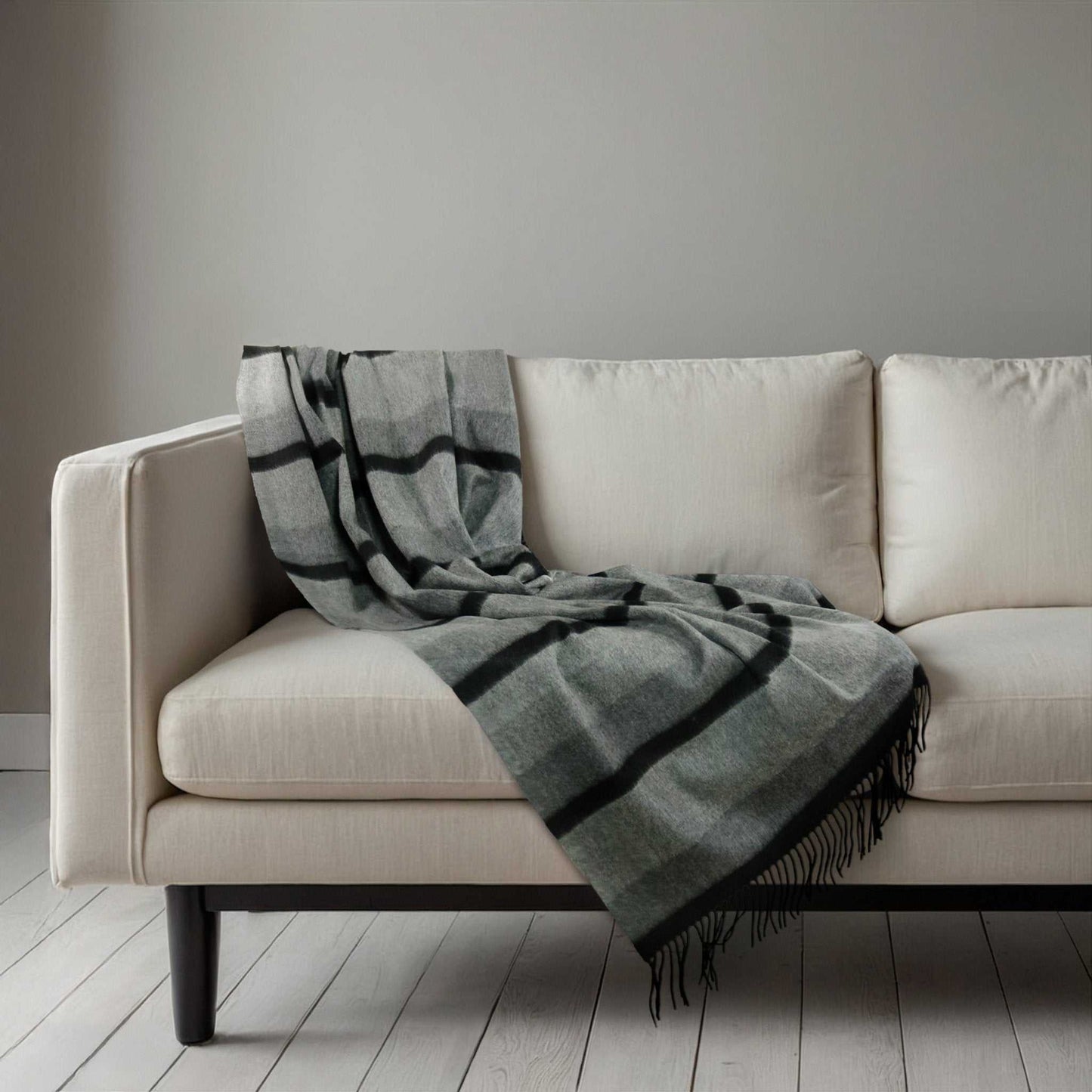 Cashmere Woven Throw - Cashmere Woven Throw | Premium Quality in black and grey stripes with fringe, laid over a modern cream couch for elegant decor.