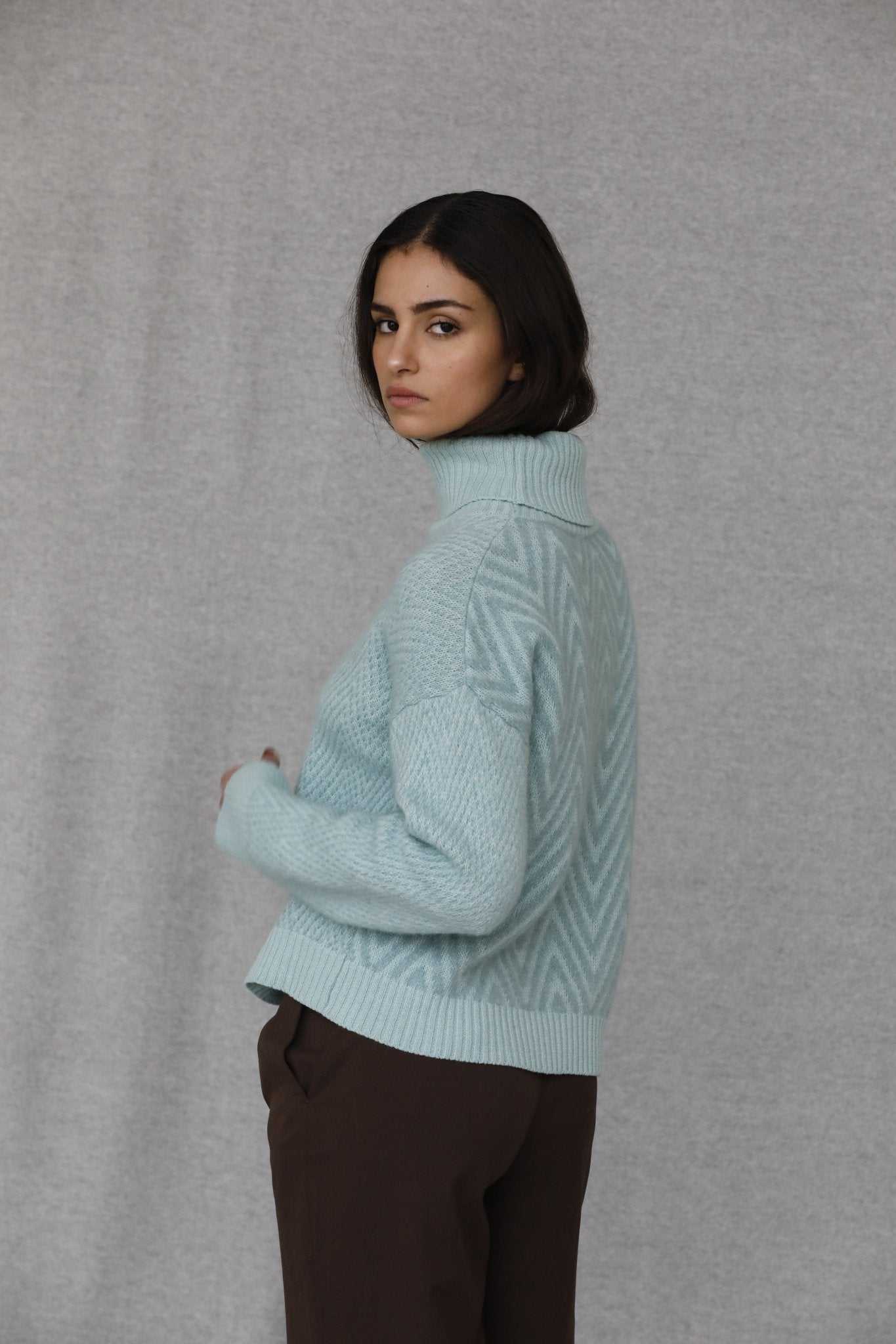 Side view of Penelope Chevron Wool Turtleneck in pastel blue, showcasing detailed chevron pattern and high turtleneck collar.