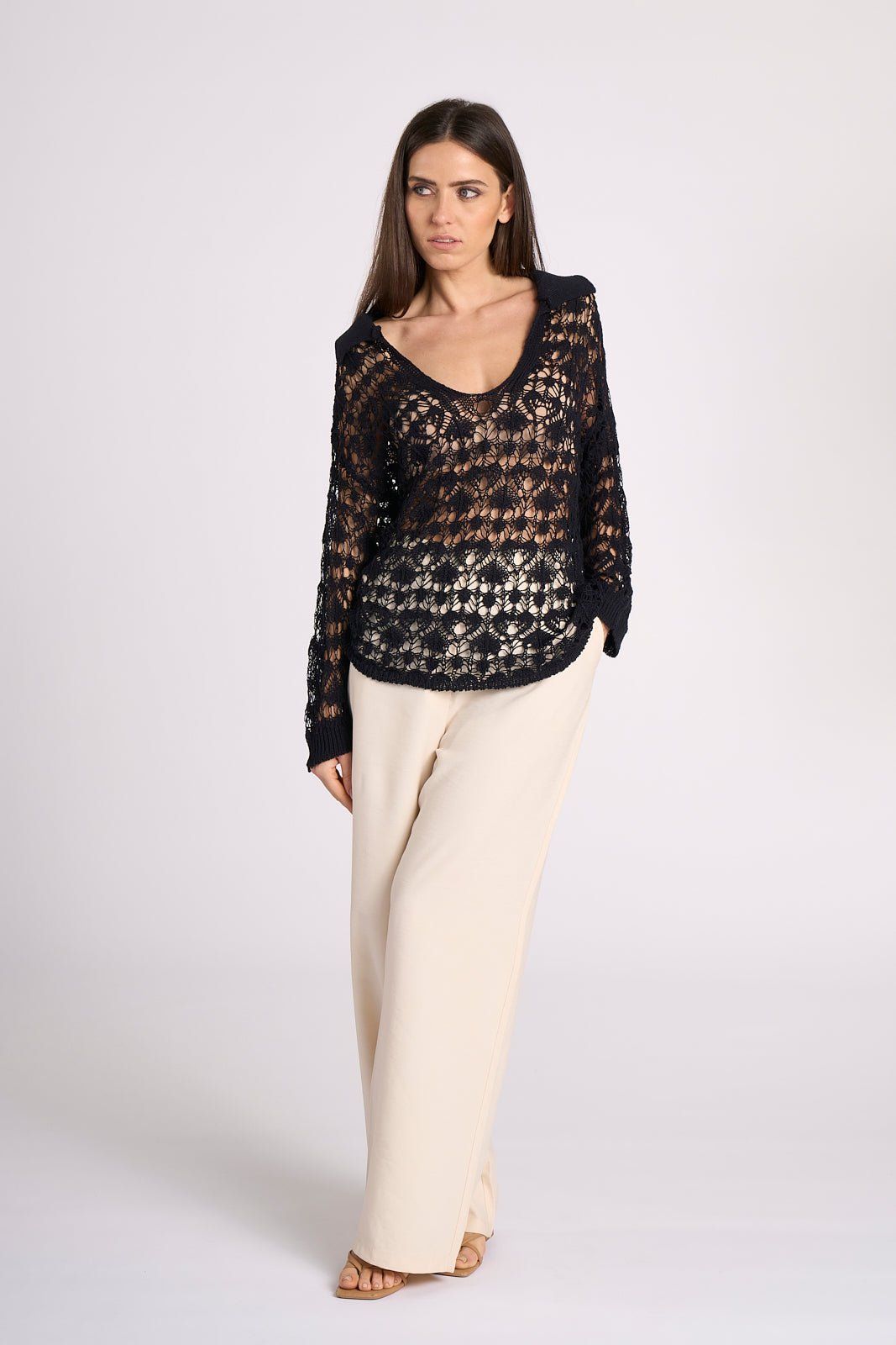 Ines Crochet Cotton Maxi Polo in black by Tenné, styled with cream trousers, highlighting sheer crochet texture and long-sleeve silhouette.