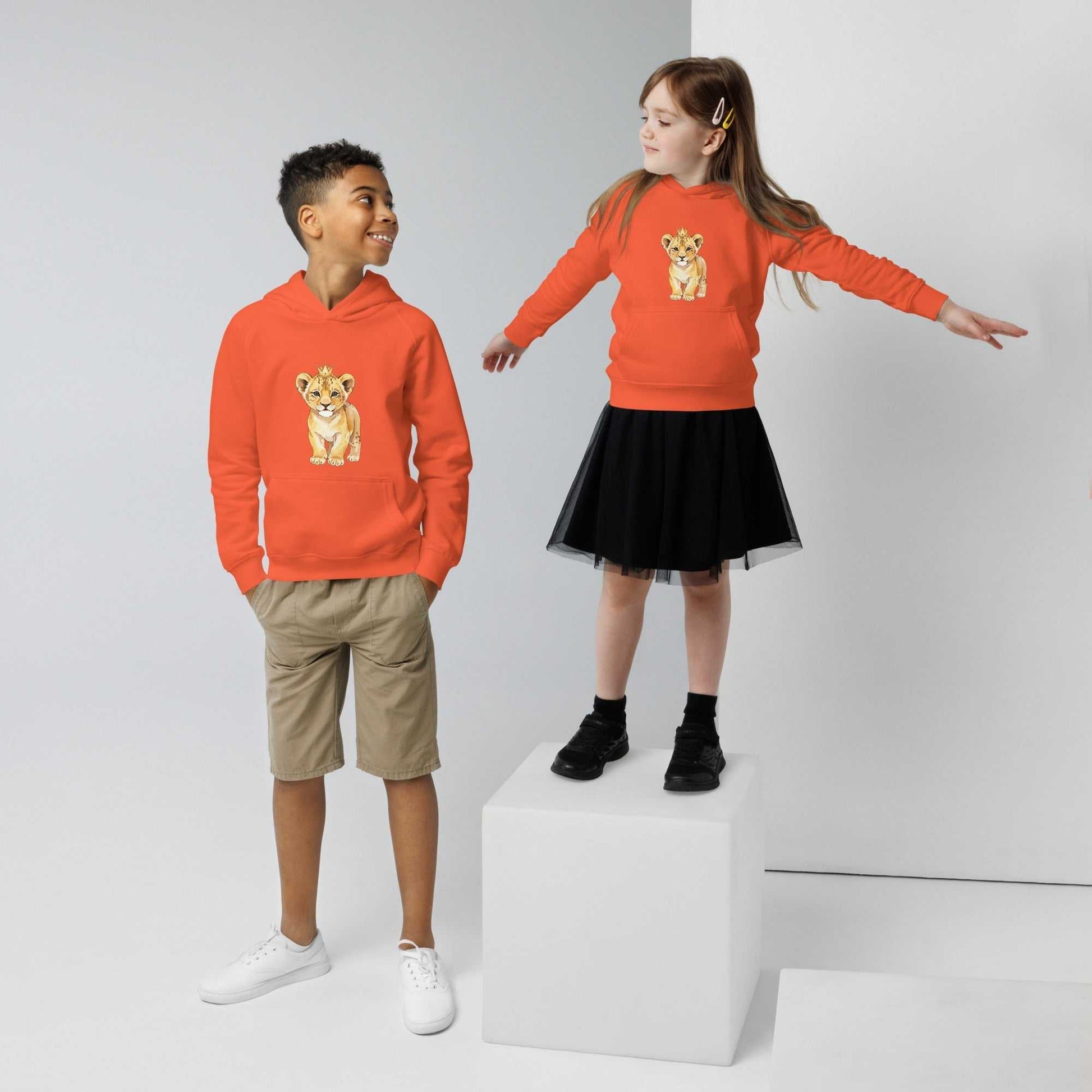 Boy and girl in orange kids eco hoodies with baby lion design. Vibrant organic cotton hoodies for fun and comfort.
