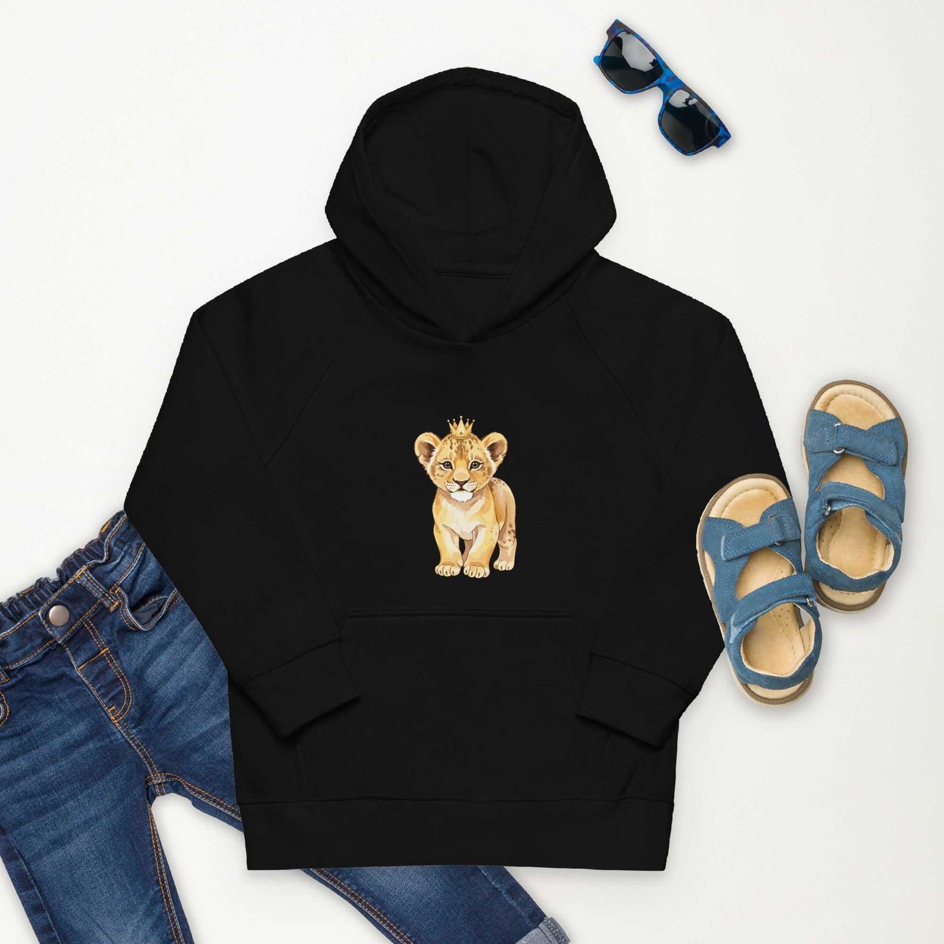 Kids eco hoodie with baby lion design in black, styled with jeans, sandals, and sunglasses. Made from organic cotton for natural comfort.