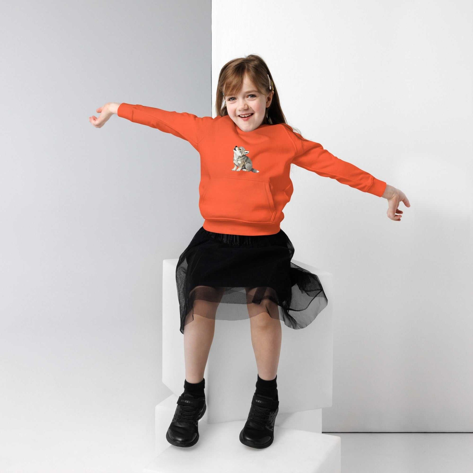 Orange kids eco hoodie featuring a baby wolf illustration, worn by a girl. Organic cotton hoodie designed for comfort and playful style.