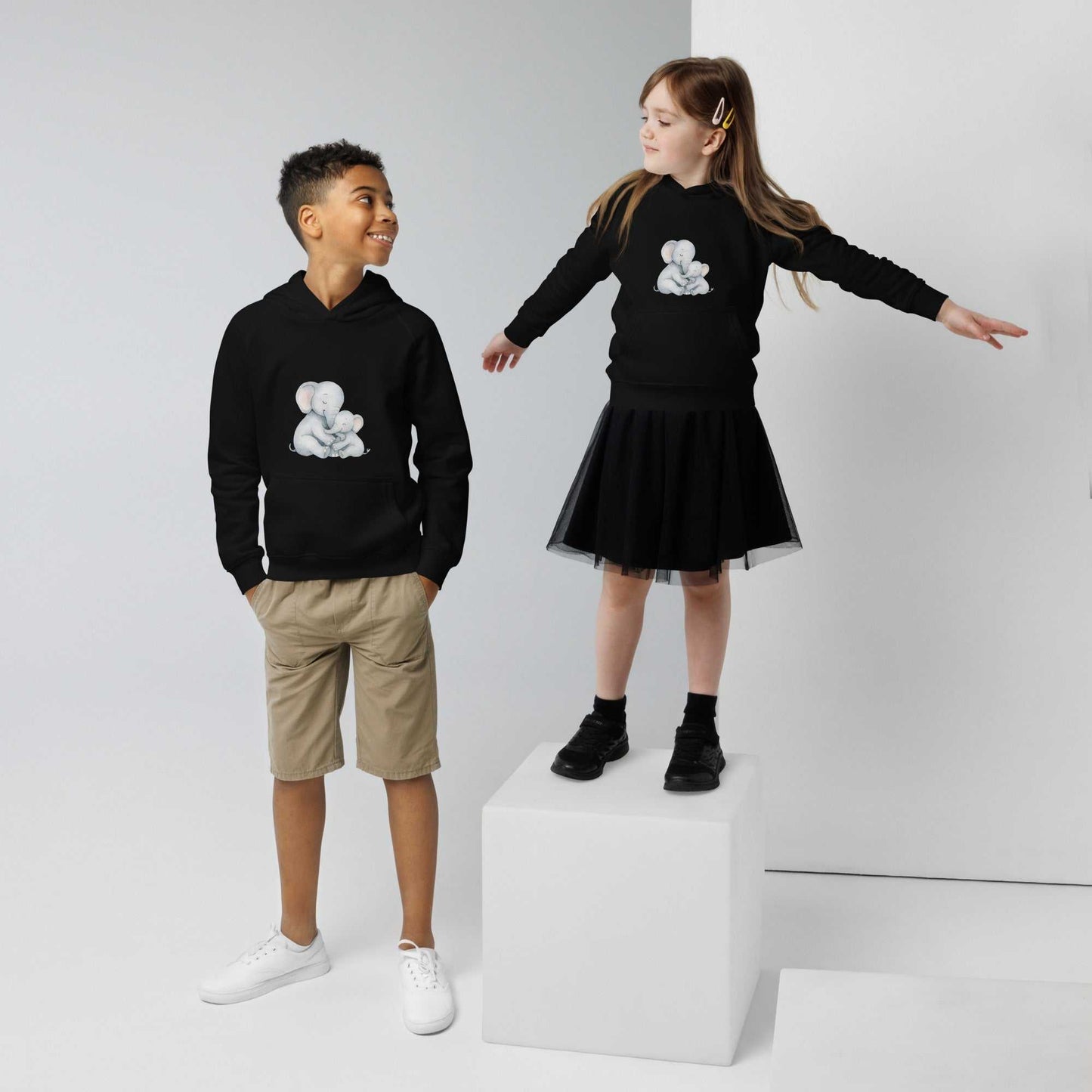 Matching black kids eco hoodies with mom & baby elephant design, worn by two children showcasing cozy, sustainable fashion.