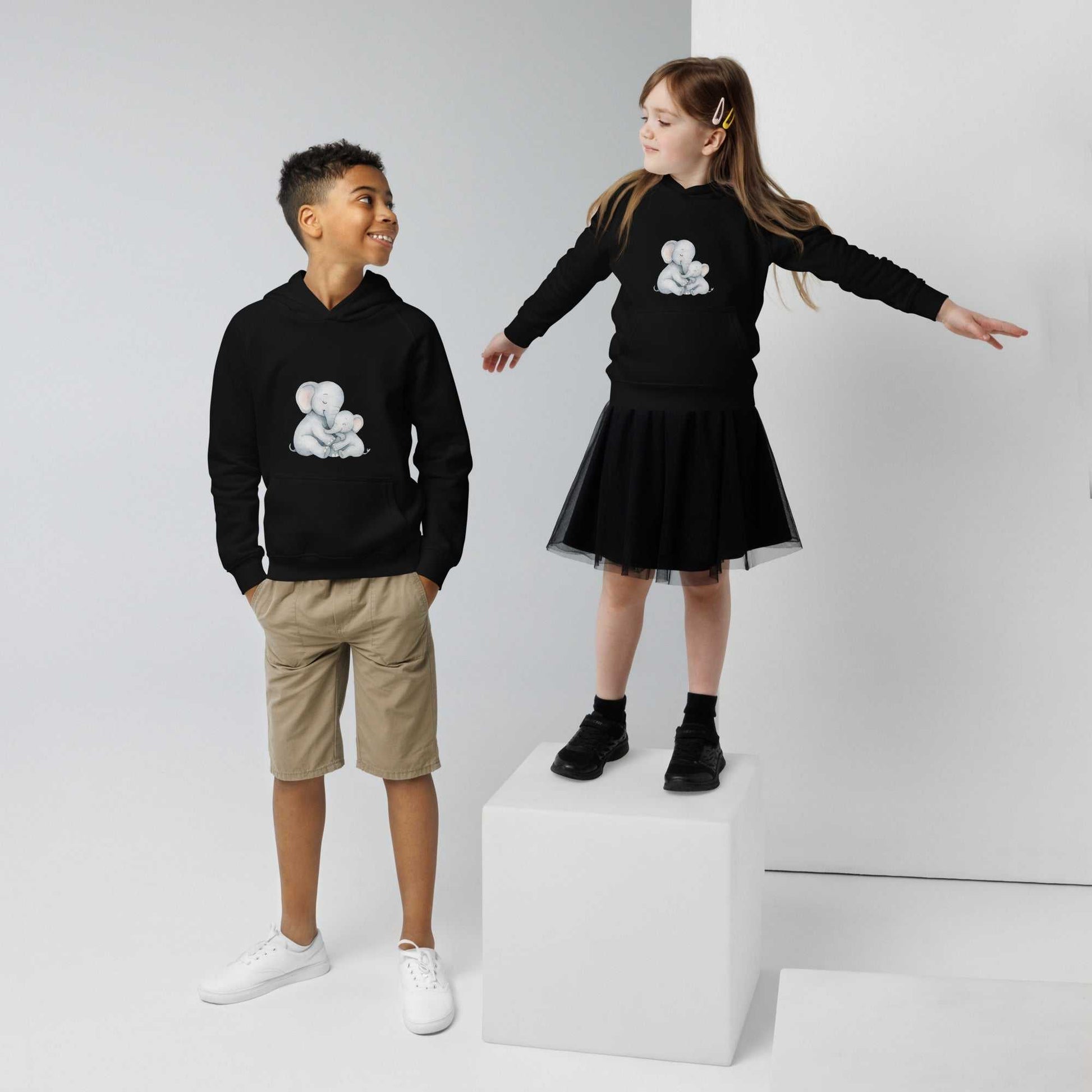 Matching black kids eco hoodies with mom & baby elephant design, worn by two children showcasing cozy, sustainable fashion.