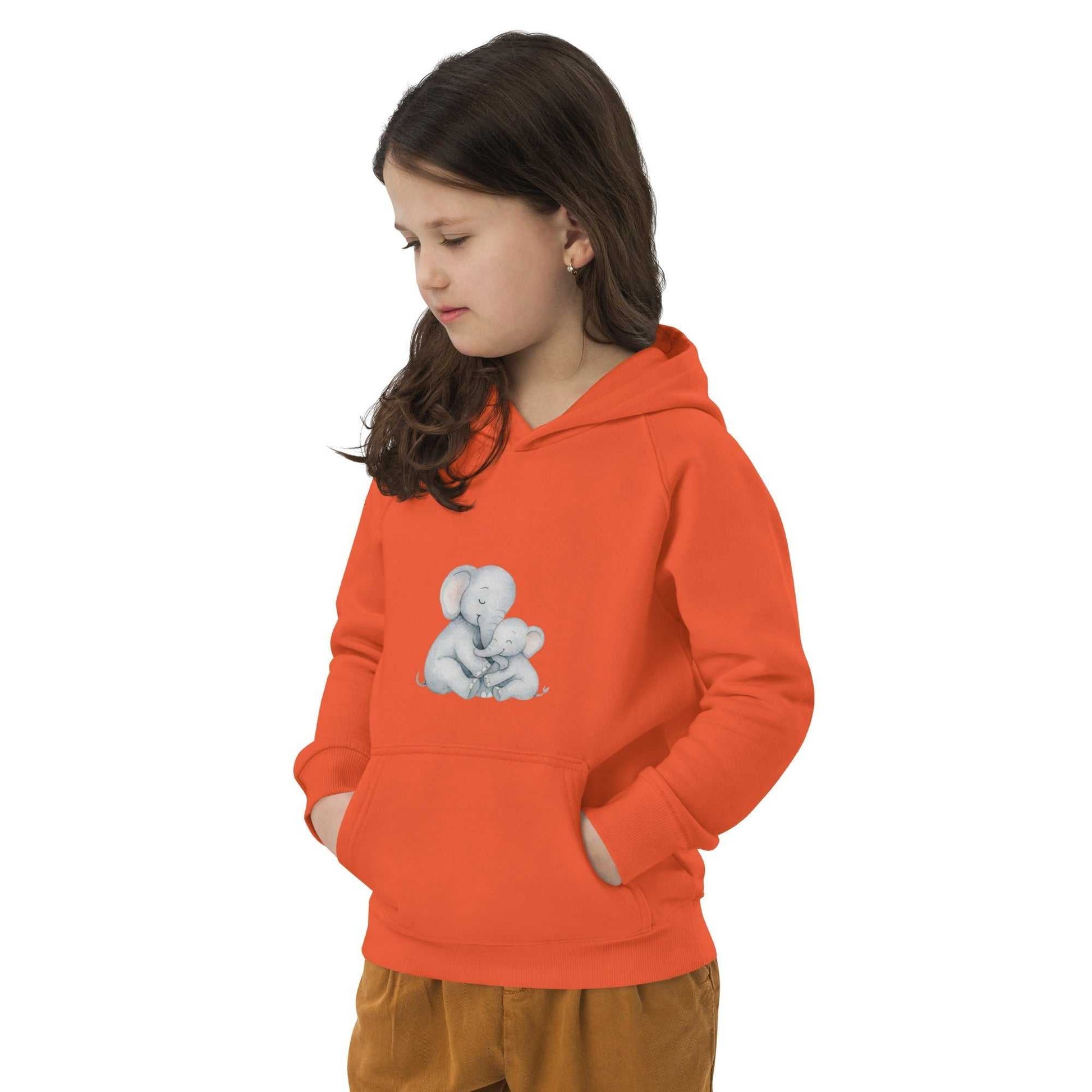 Child in orange Kids Eco Hoodie with hands in pockets, featuring a cute Mom & Baby Elephant design for warm, organic comfort.