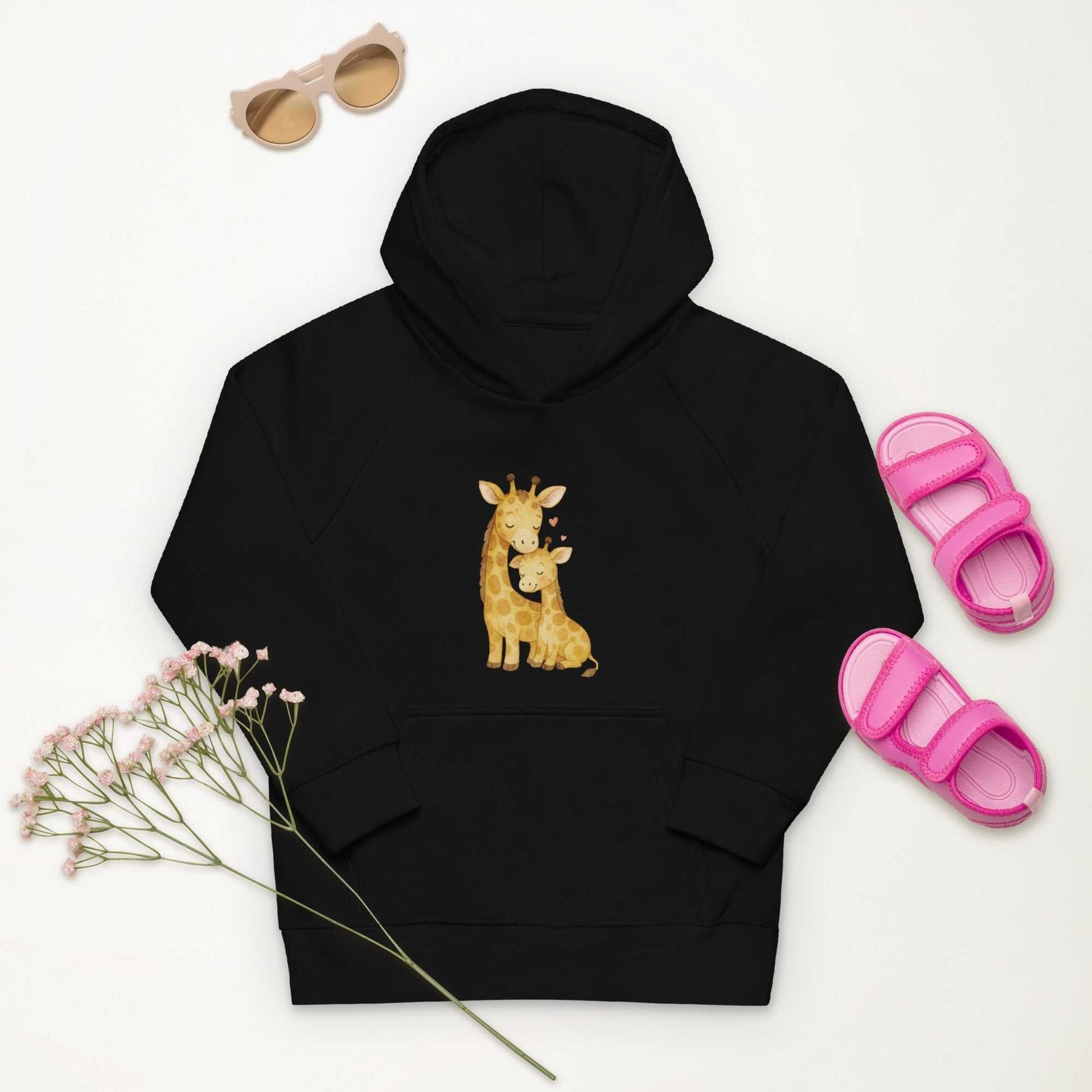 Black kids eco hoodie with giraffe design, styled with pink sandals and sunglasses. Organic cotton hoodie for eco-friendly kids fashion.