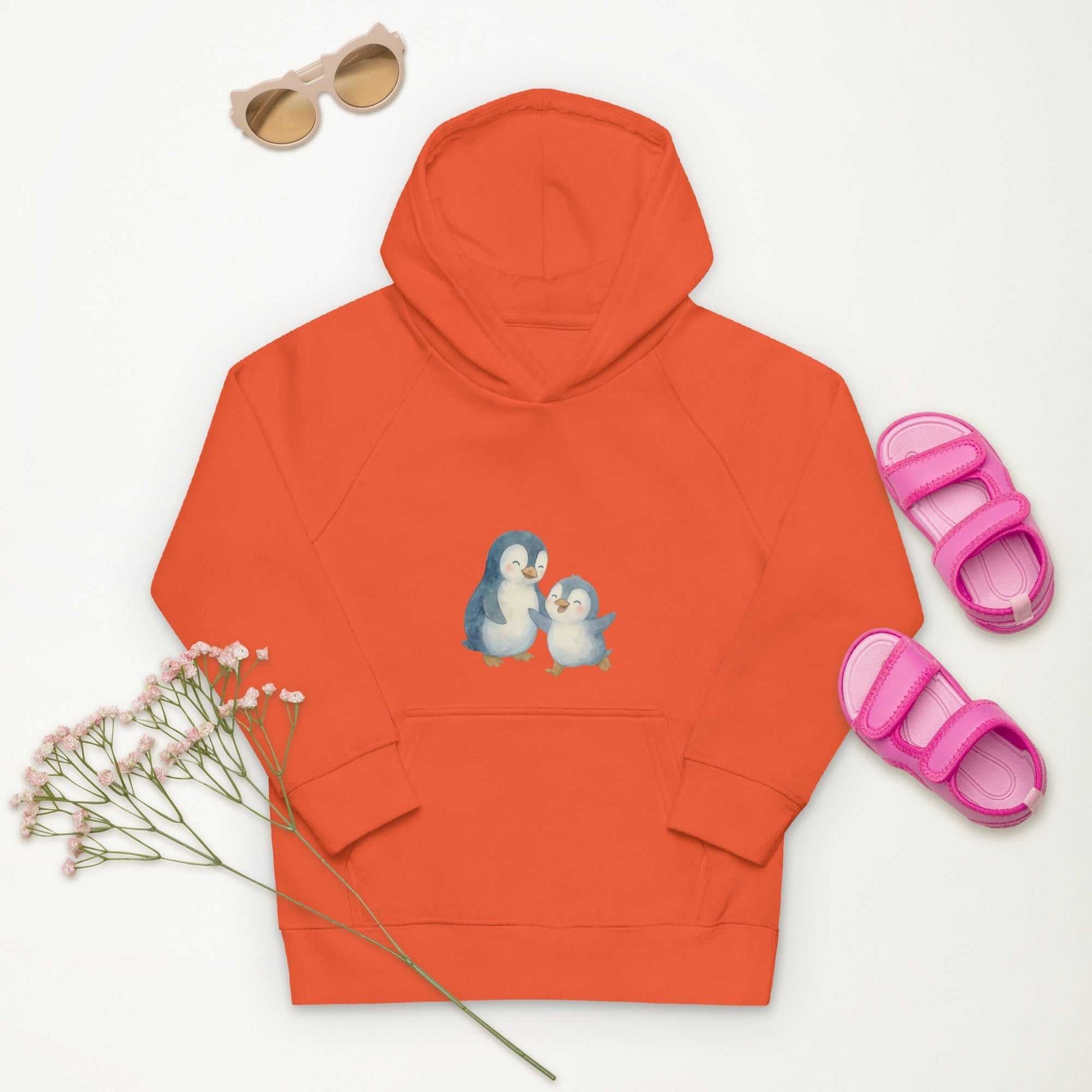 Orange Organic Cotton Kids Hoodie with penguin artwork, paired with pink sandals and sunglasses for a vibrant kids style