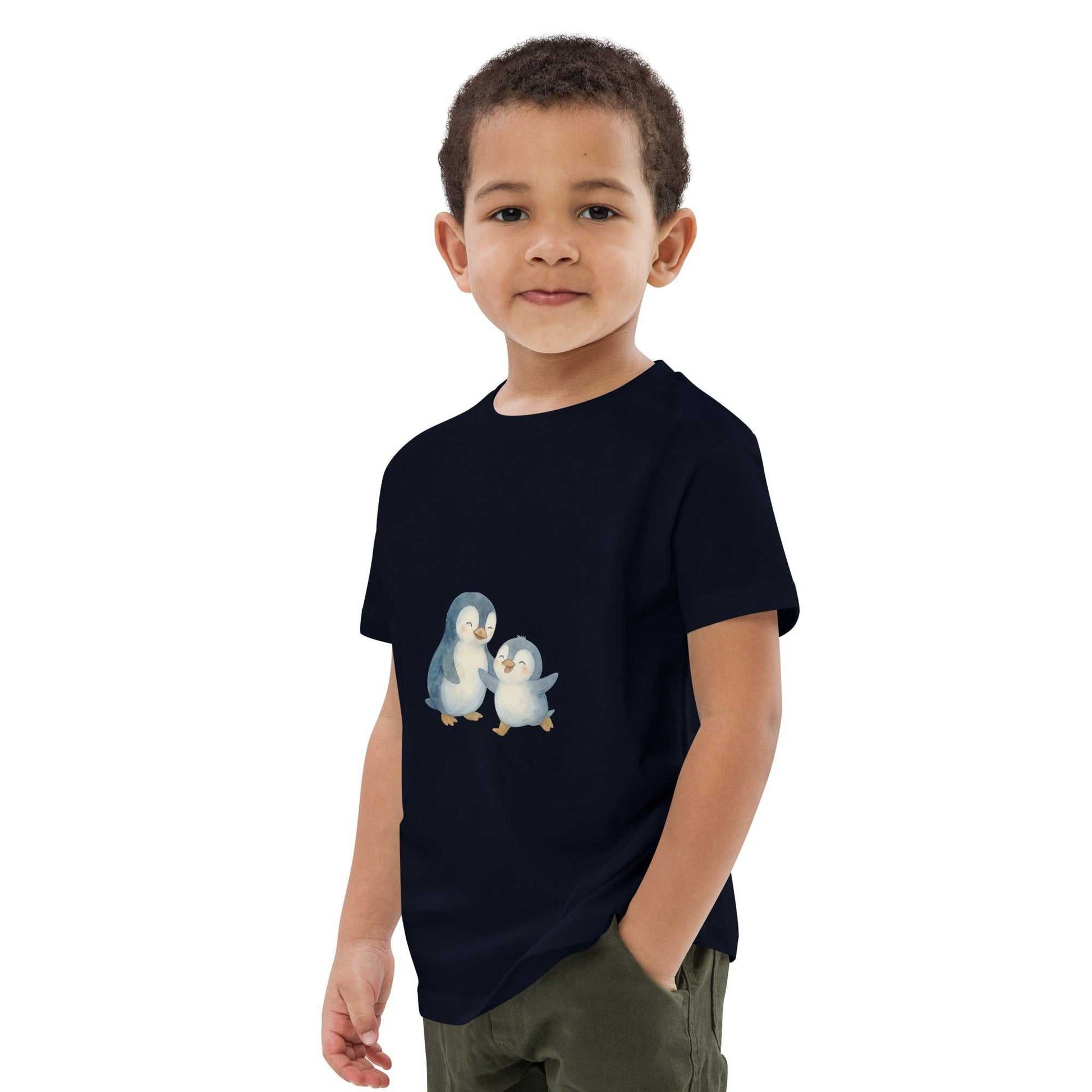 Boy wearing navy kids organic cotton penguin t-shirt. Features eco-friendly penguin design on GOTS certified cotton.