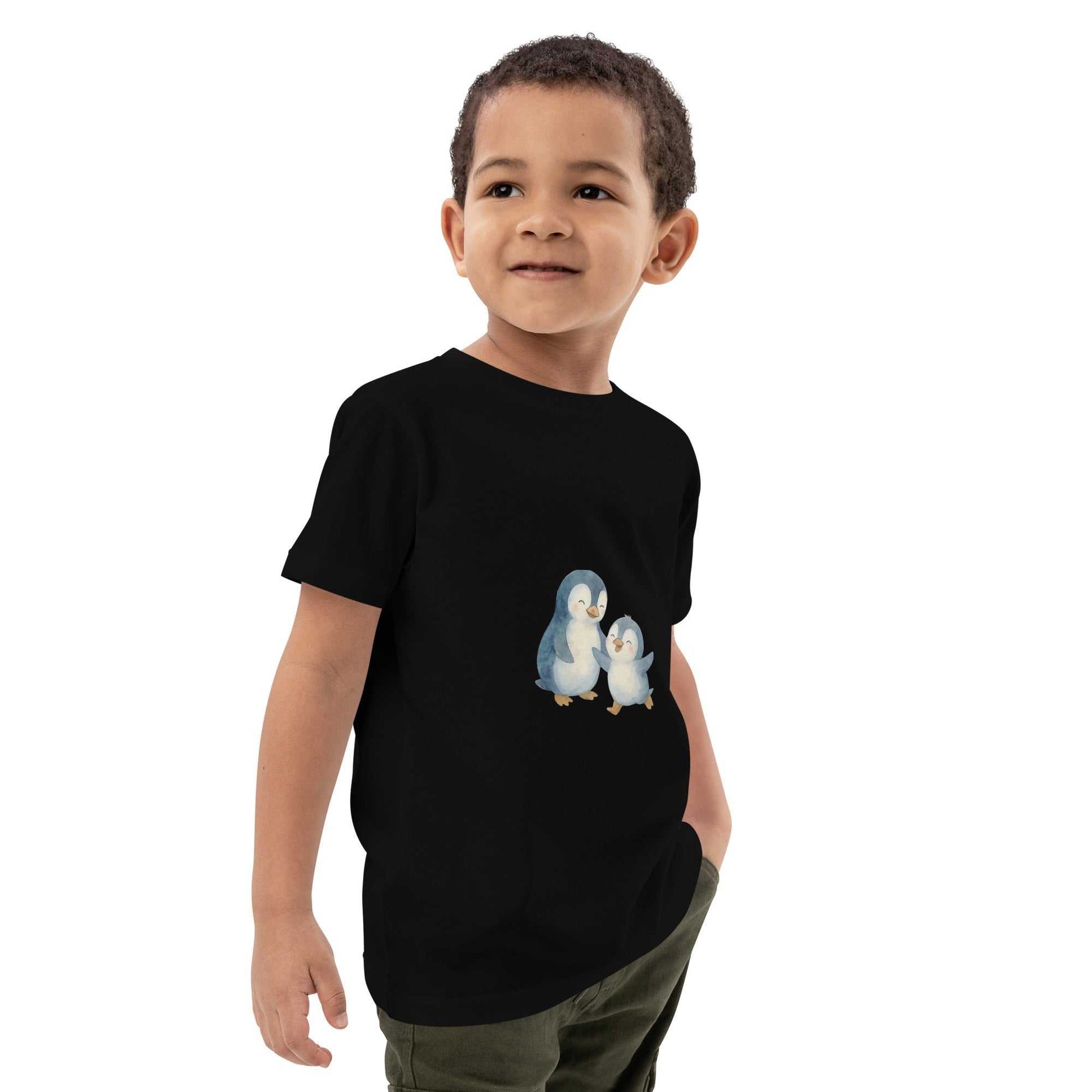 Side view of boy wearing black kids organic cotton penguin t-shirt. Features eco-friendly penguin design on soft certified cotton.