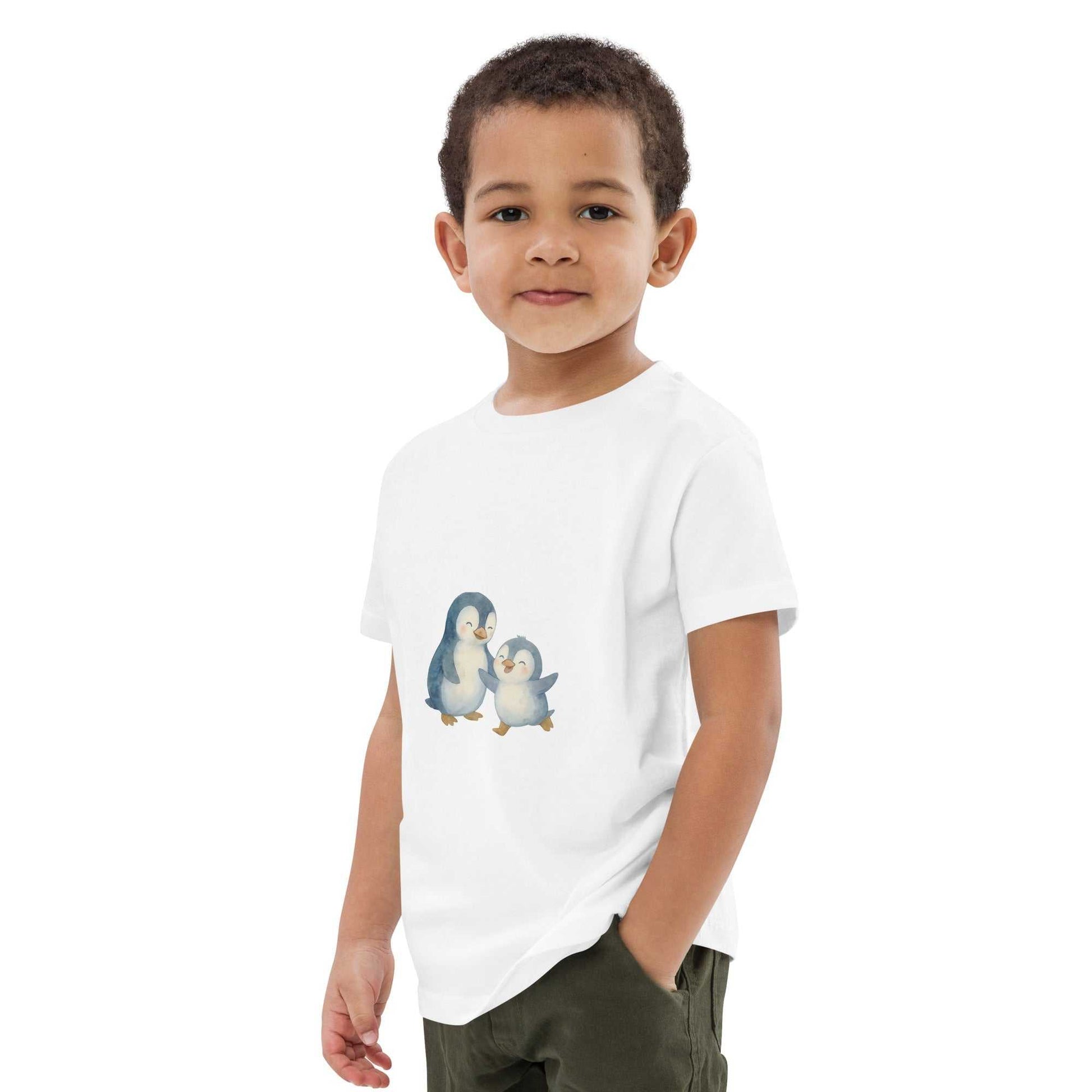 Boy modeling white kids organic cotton penguin t-shirt. Features adorable penguin print and eco-conscious materials.