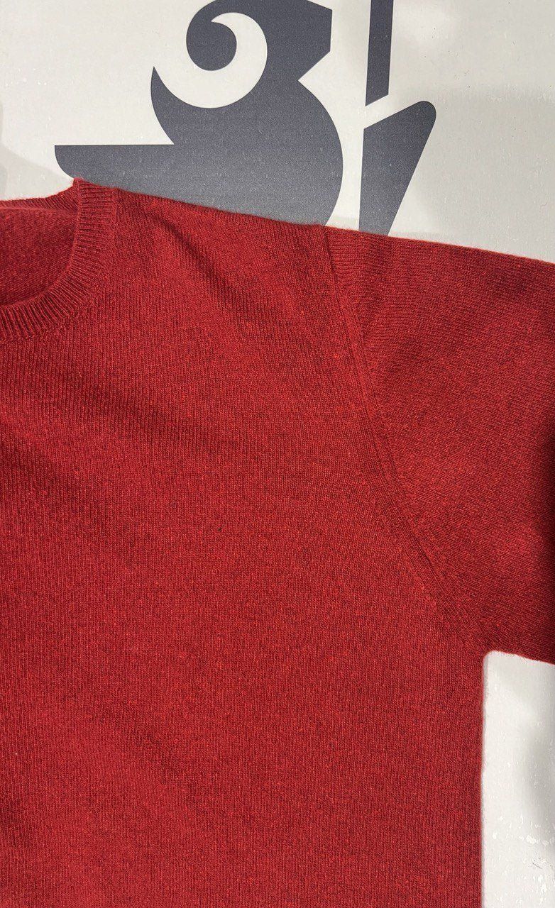 Close-up of red regenerated cashmere sweater fabric and stitching. Showcasing soft texture and eco-conscious craftsmanship.