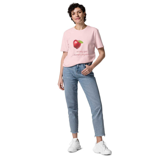 Light pink unisex organic cotton t-shirt with red apple graphic and 'Not every apple becomes a fairytale' text. Eco-friendly and witty fashion.