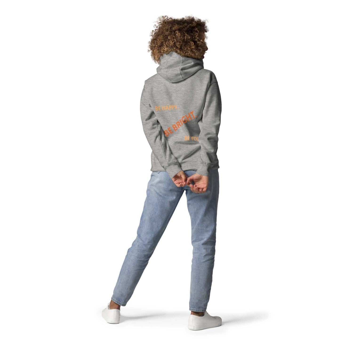 Model showing back of gray unisex hoodie with orange text 'Be Happy. Be Bright. Be You.' in casual pose.