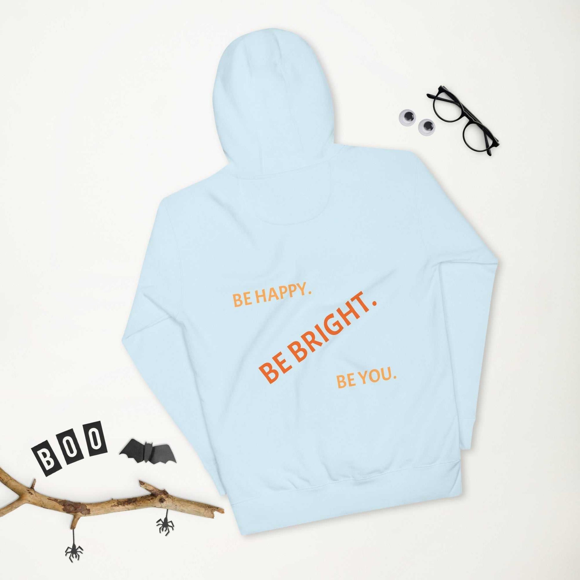 Flat lay of light blue premium unisex hoodie with motivational back print, styled with Halloween decor for seasonal appeal.