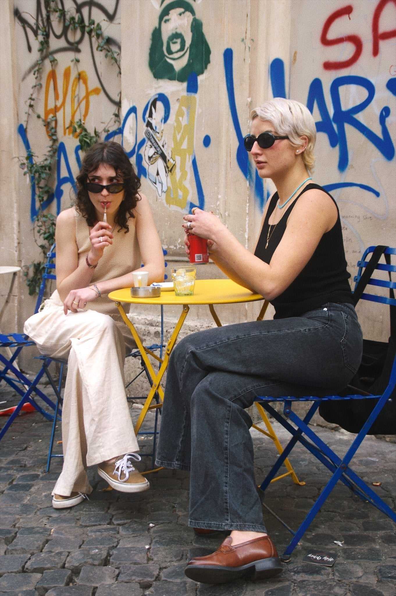 Margaret Tank Top - Sustainable Lyocell Tank Top in black and beige styled casually with flared pants and sunglasses, worn by two women at an outdoor café.